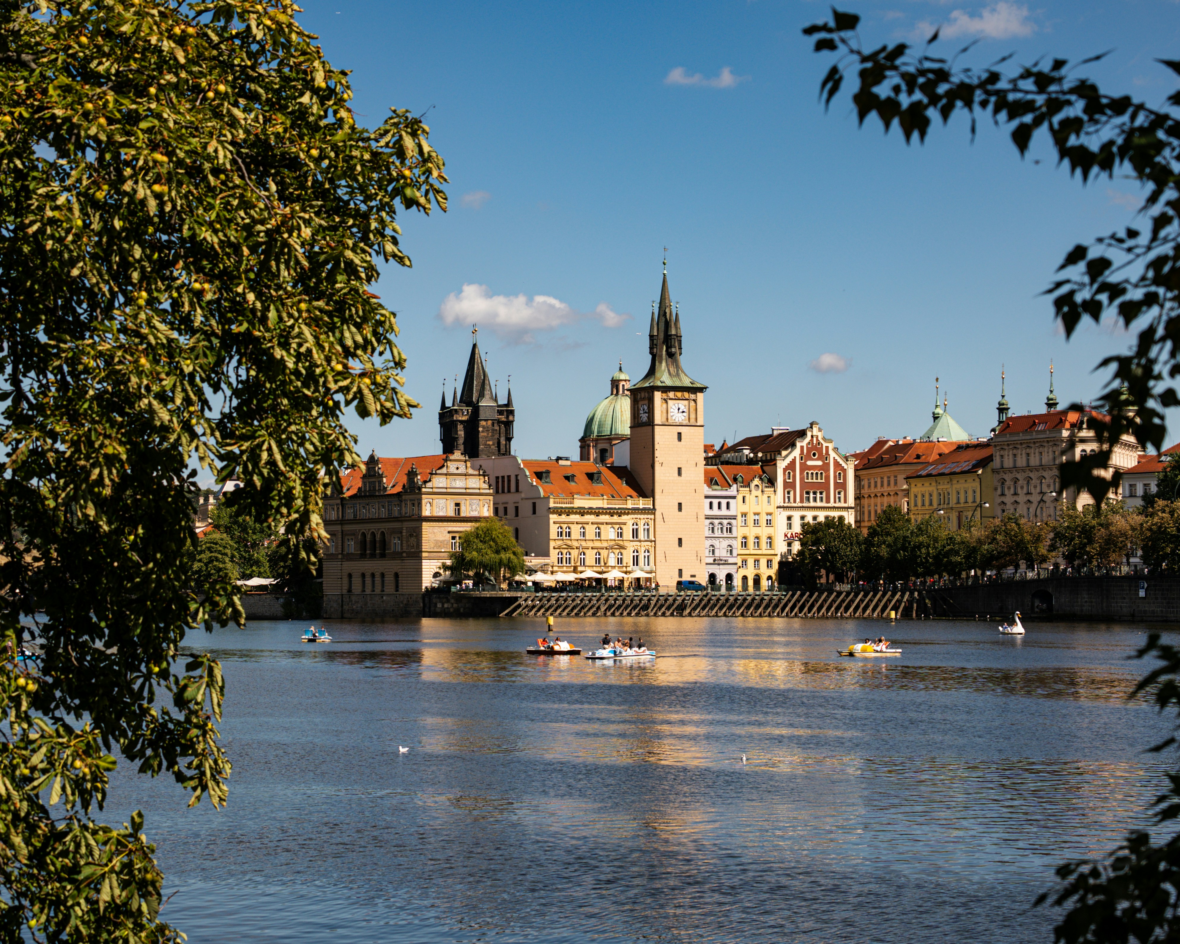 Historic buildings on river with swan boats on water.