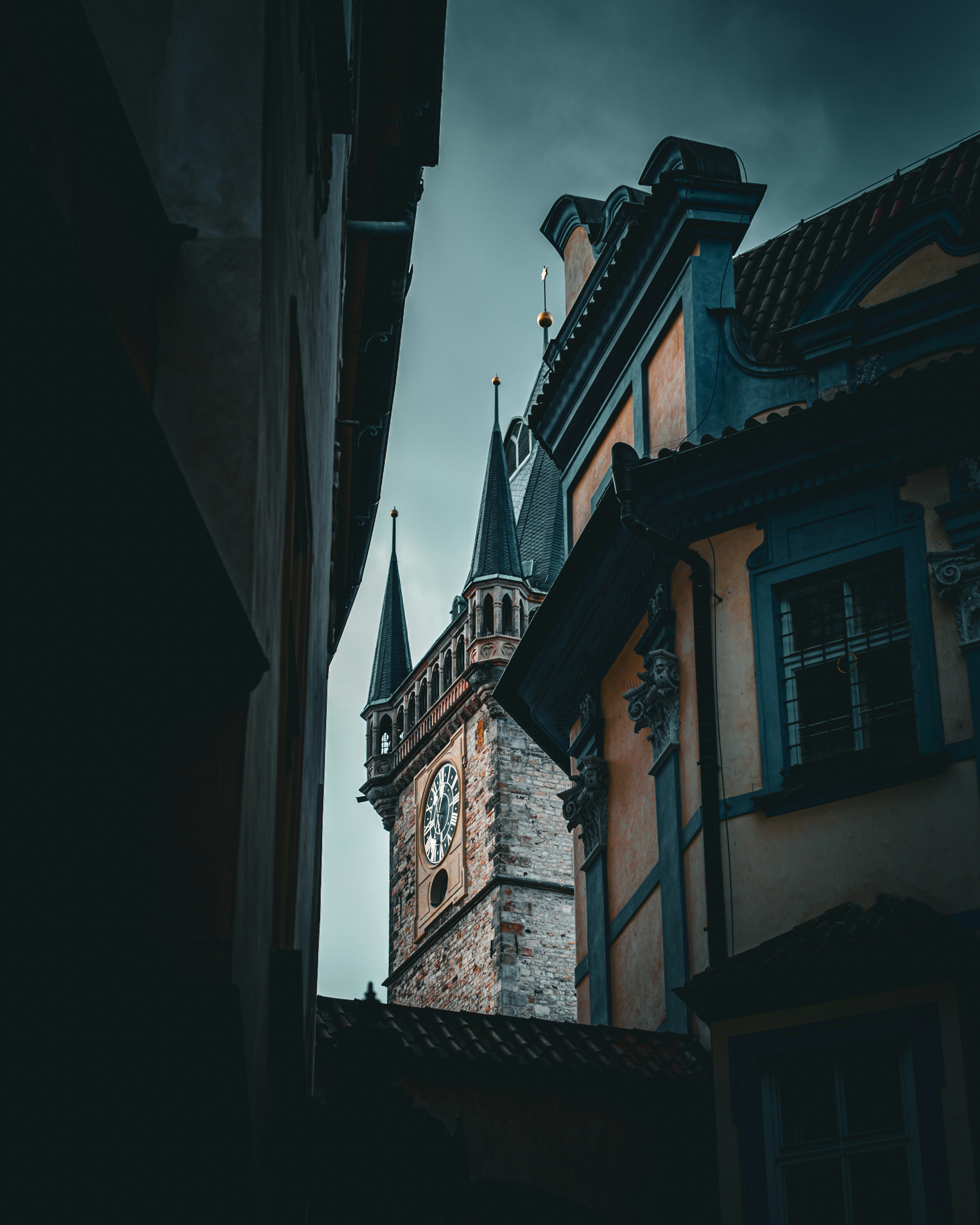 Old stone clock tower between buildings under cloudy sky