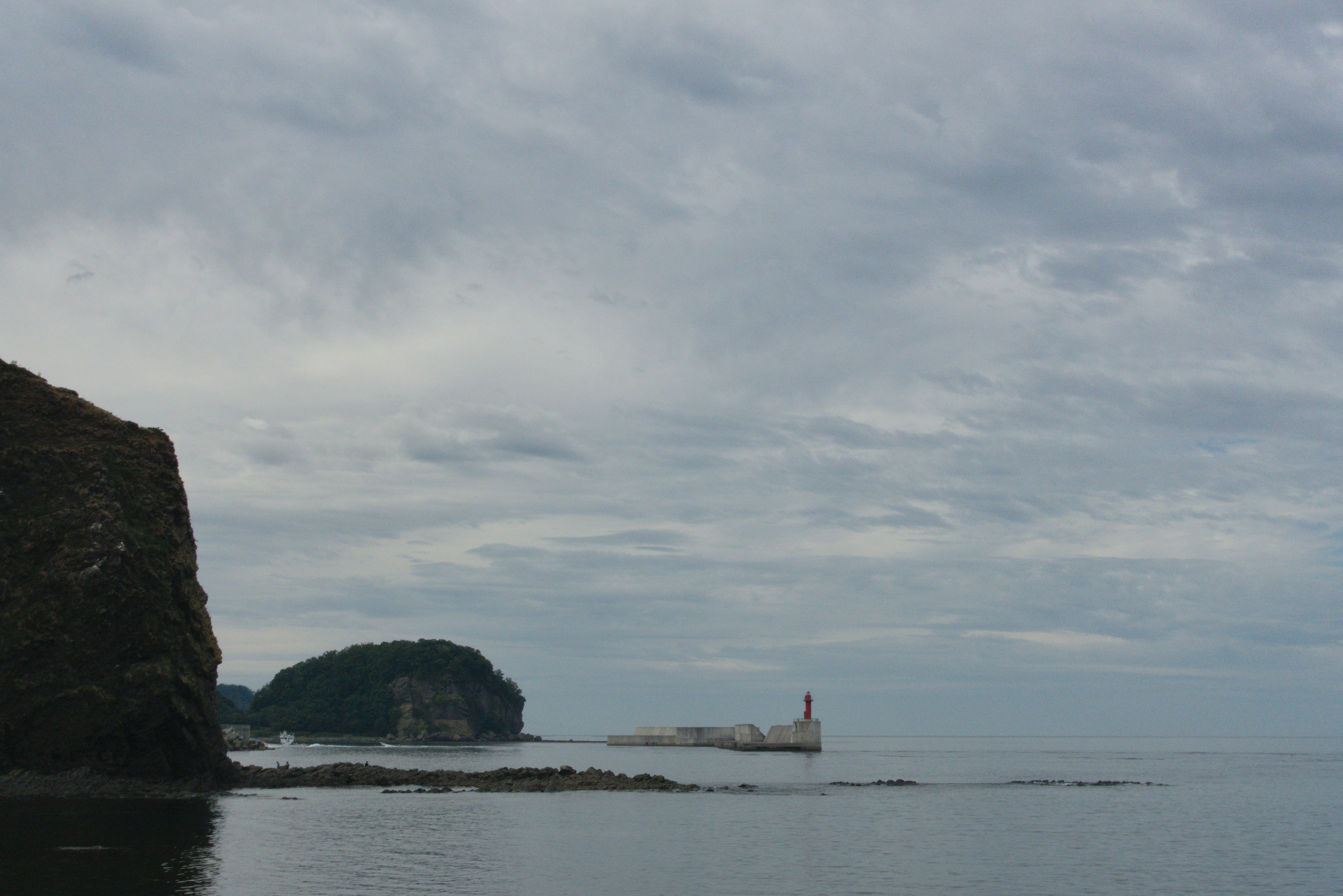 Lighthouse on a rocky coastline under cloudy sky