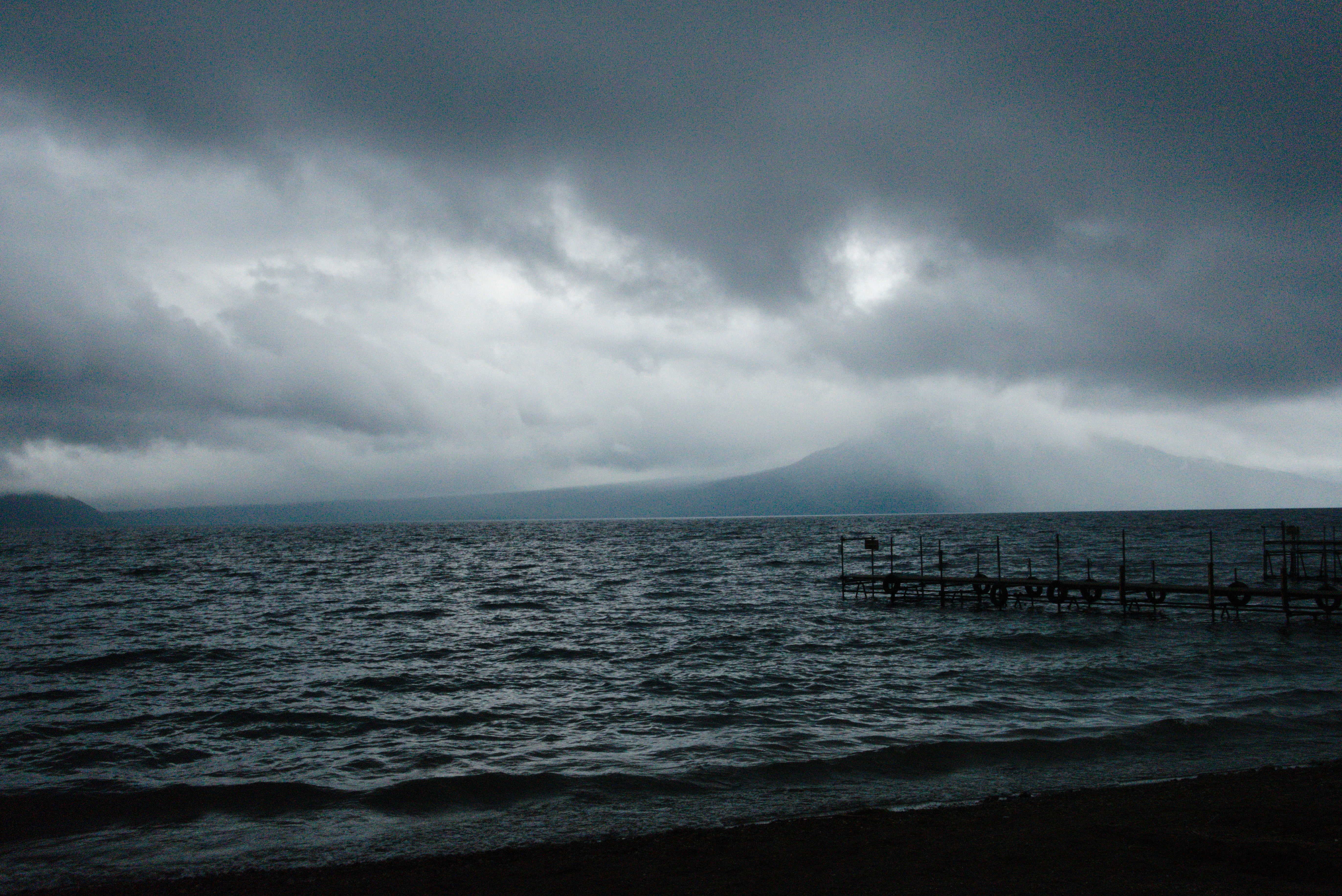 Dark storm clouds gather over a calm lake.