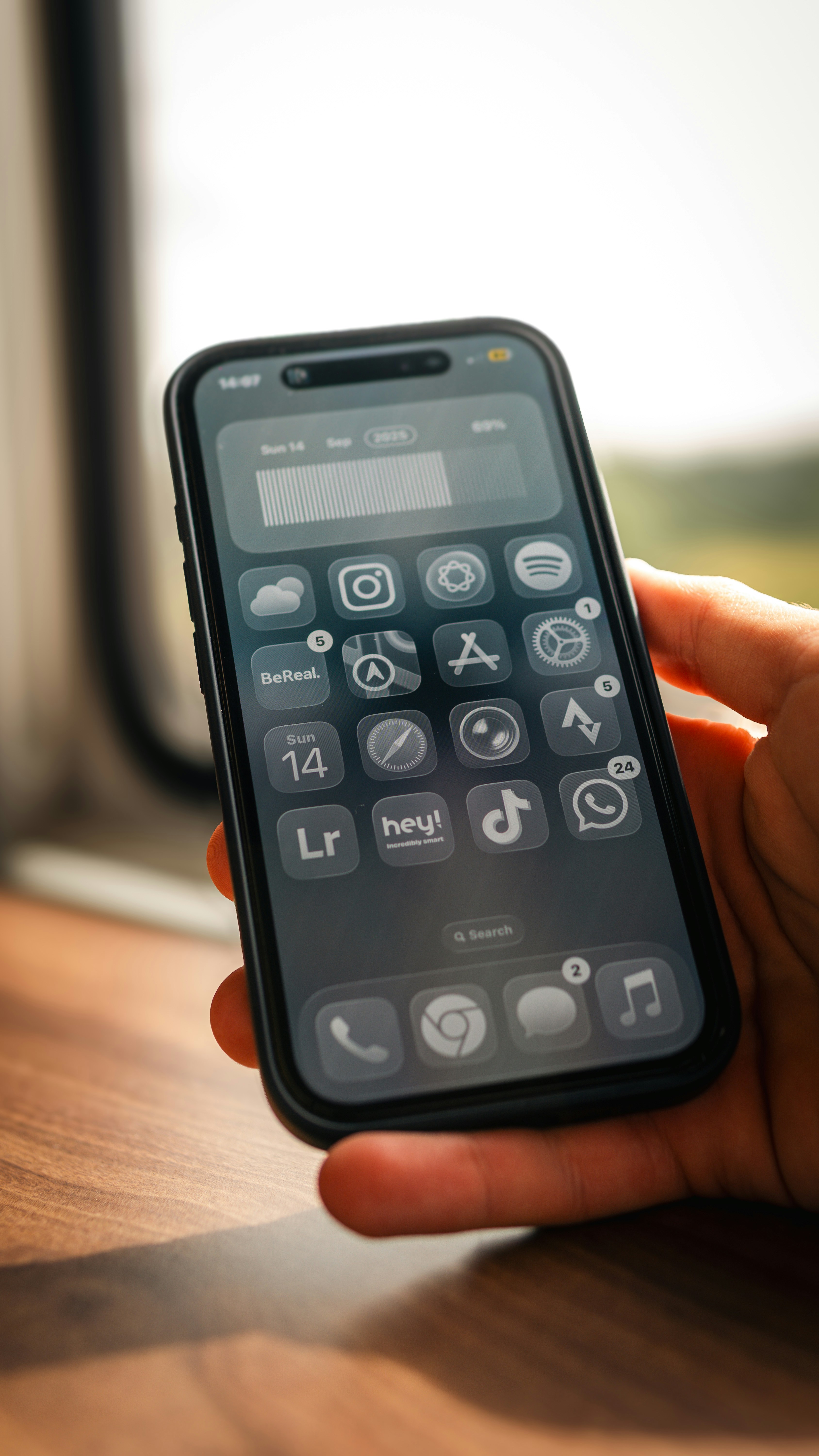 Hand holding a smartphone with a dark theme interface.