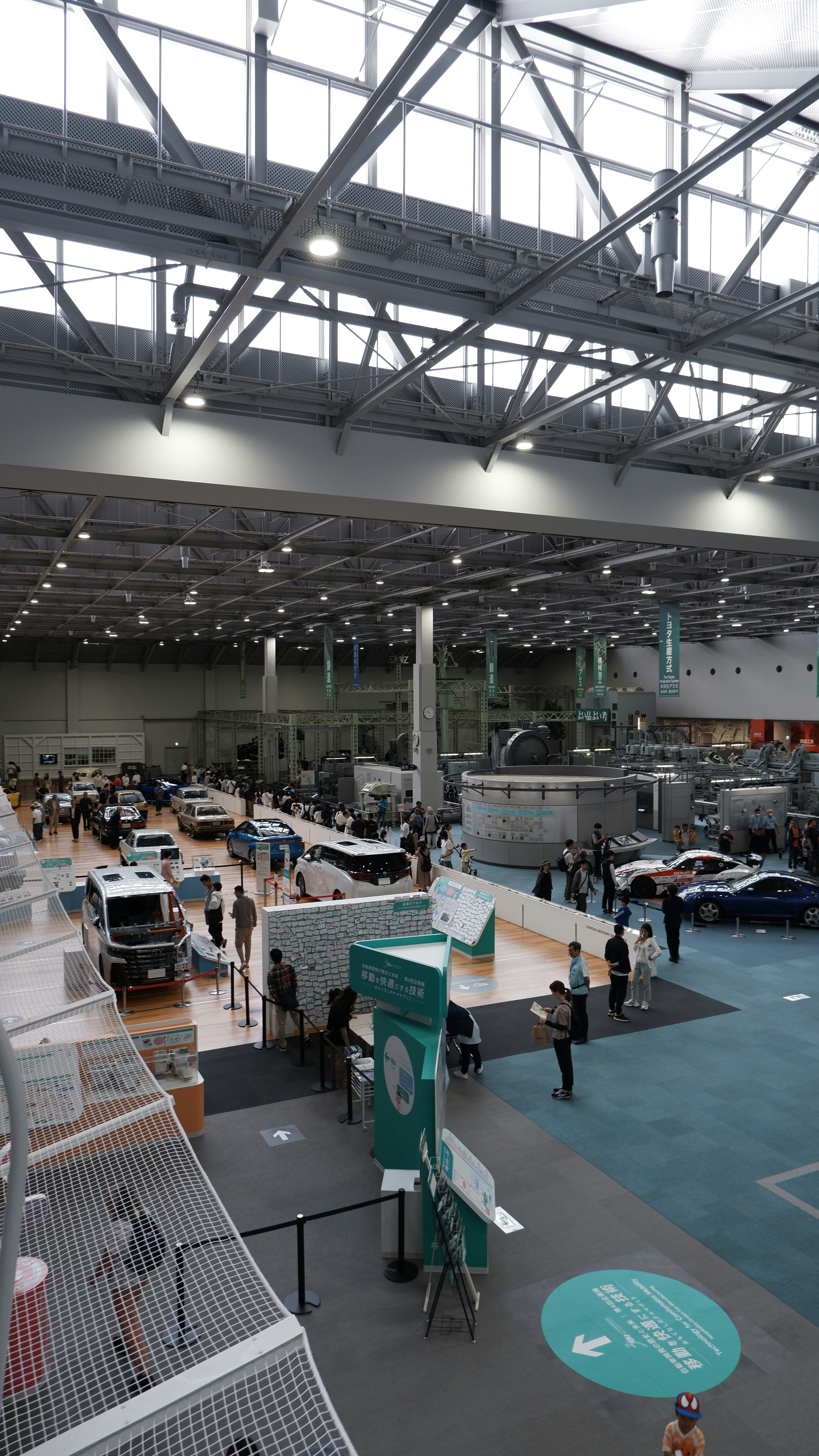 Visitors walk between modern and classic cars at an exhibition.