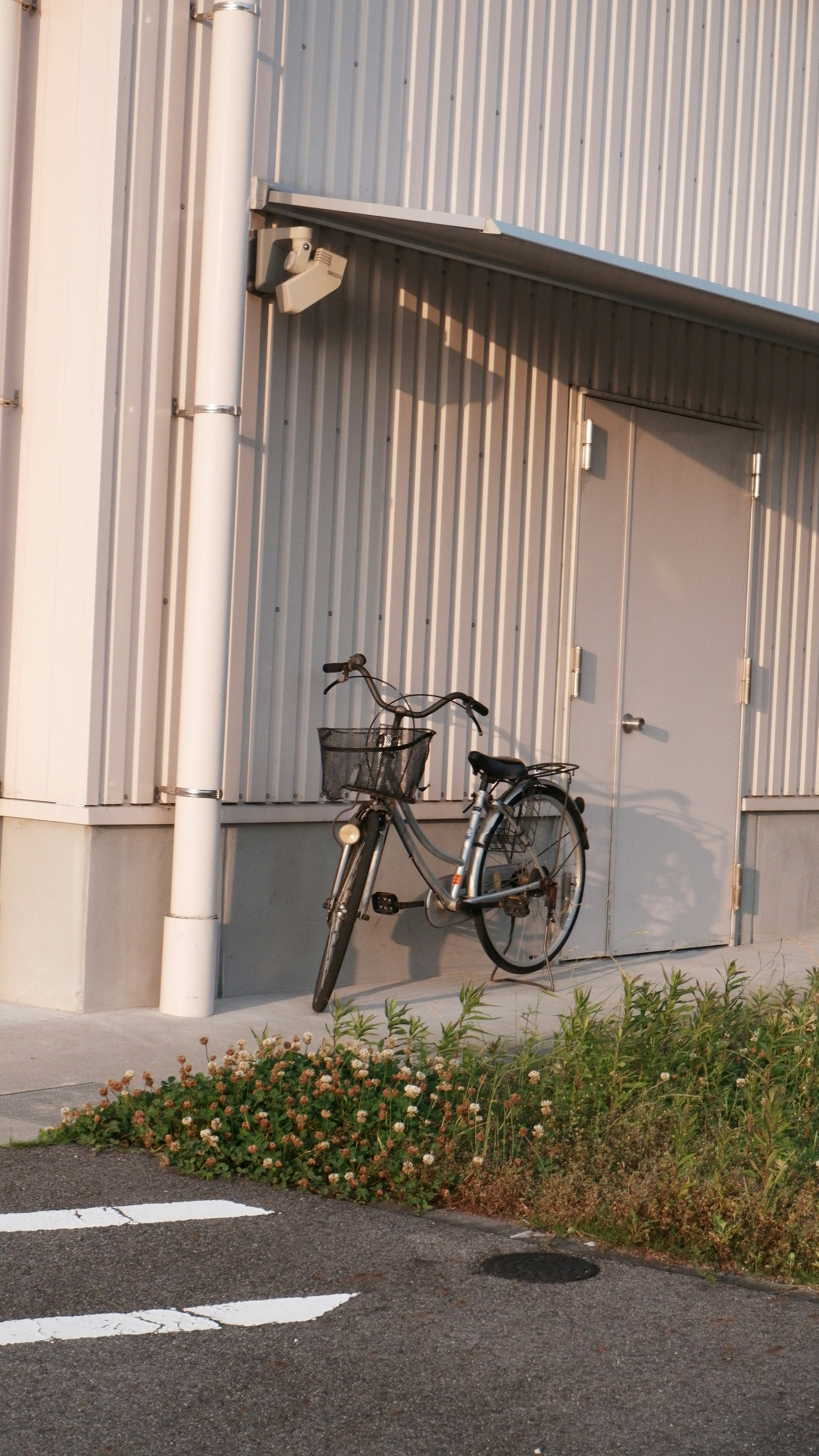 Bicycle parked against a corrugated metal building.