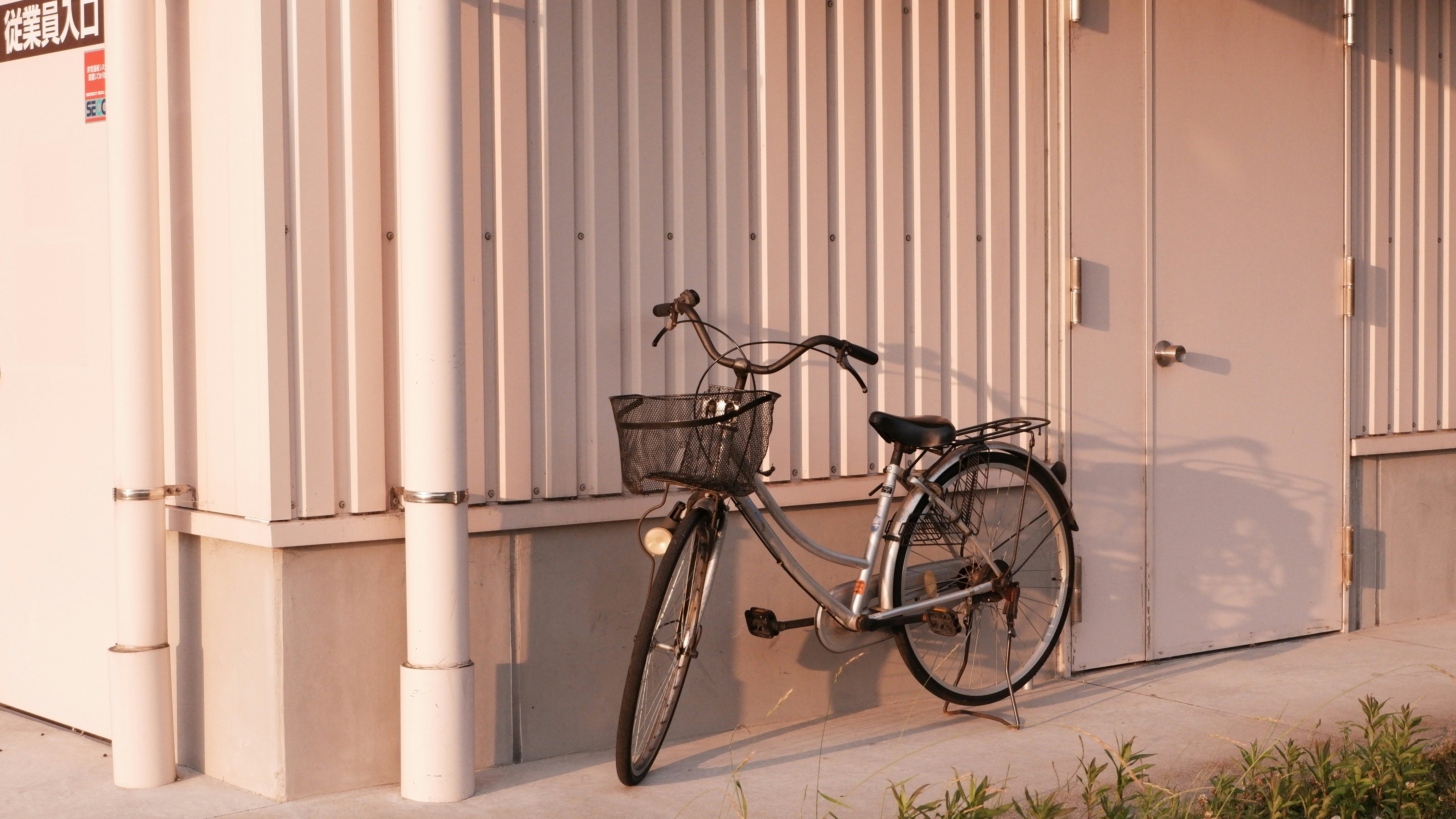 Bicycle parked next to a corrugated metal wall.