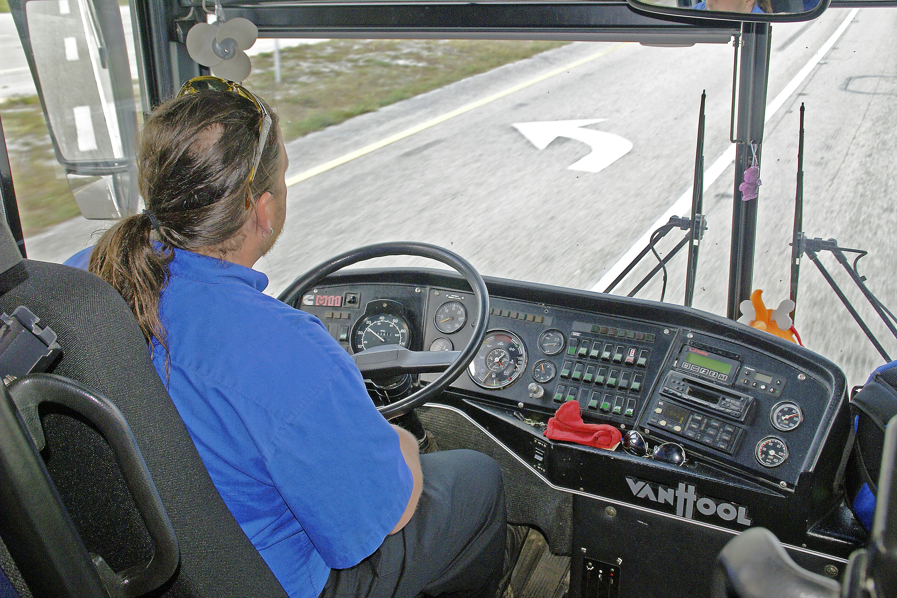 Driver in blue shirt operating a bus dashboard
