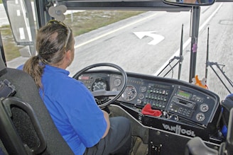 Driver in blue shirt operating a bus dashboard