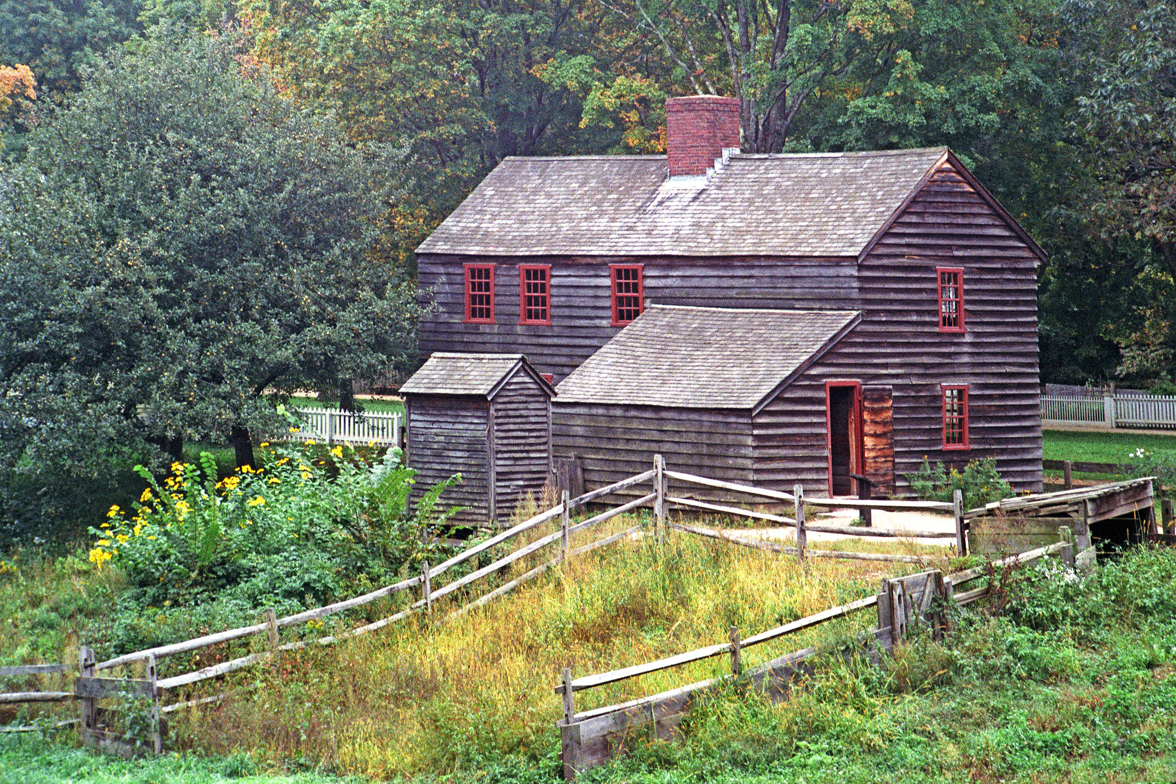 Old wooden house with red windows and a fence