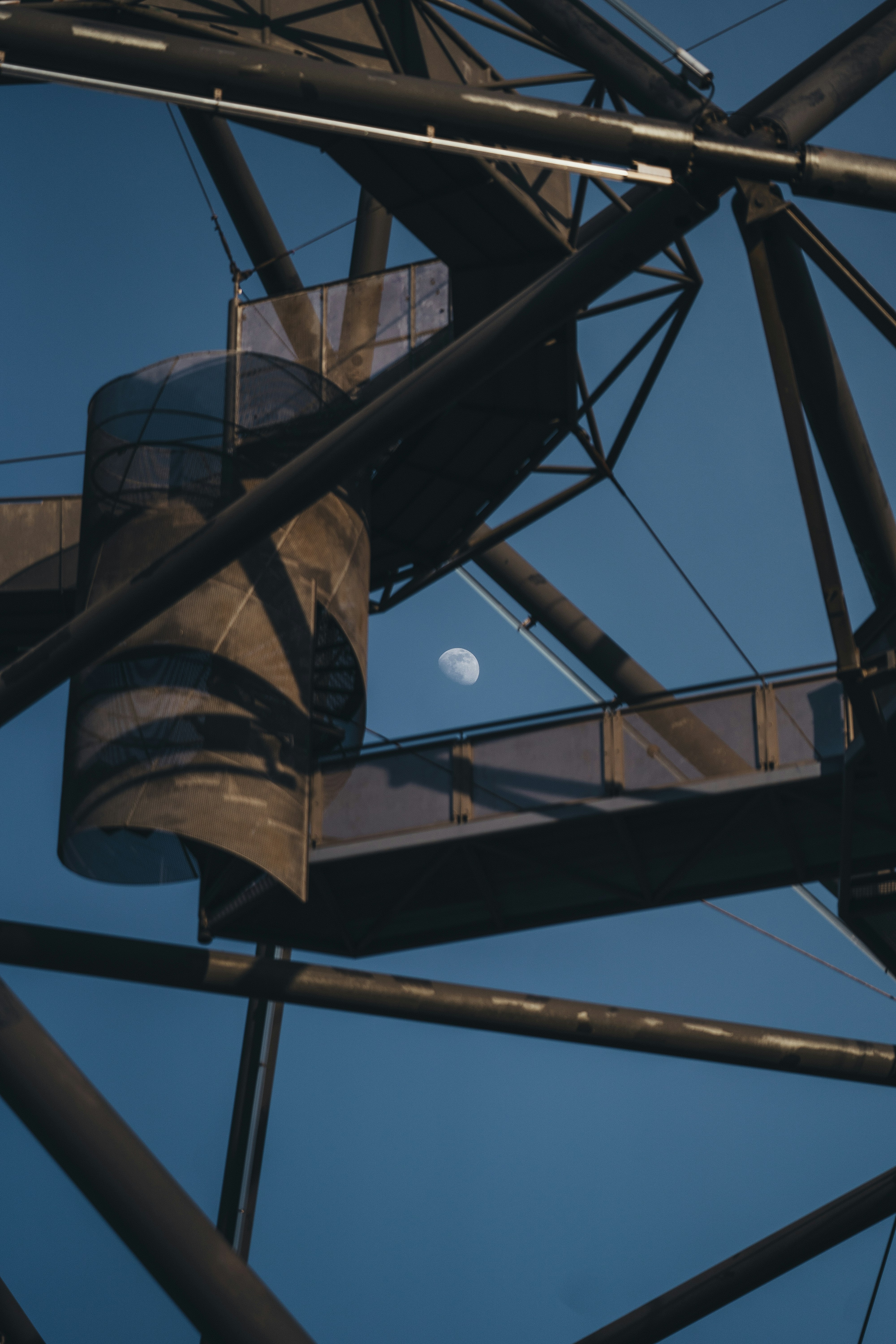 Spiral staircase with moon in clear blue sky