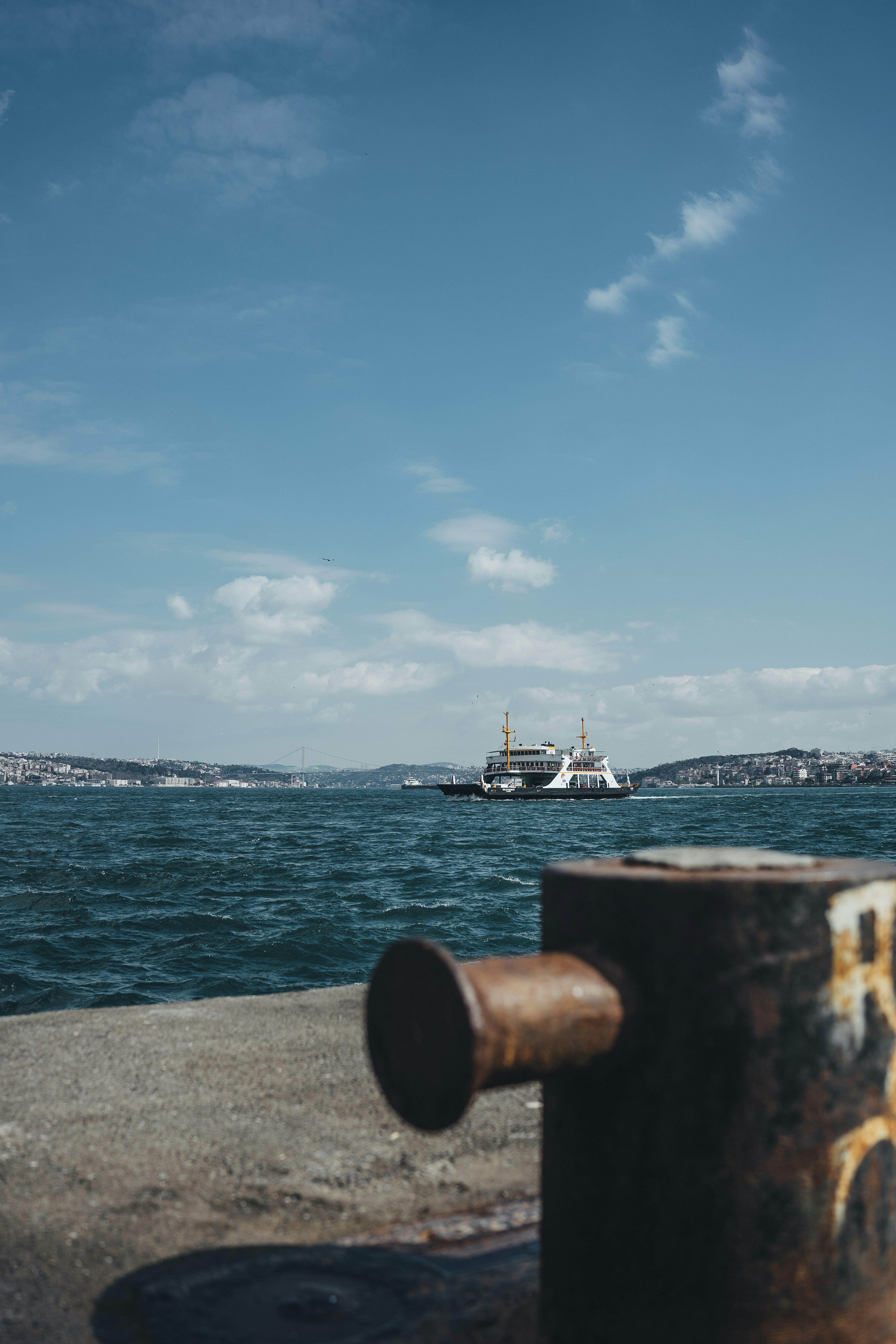 Ferry boat sails across blue water near city.