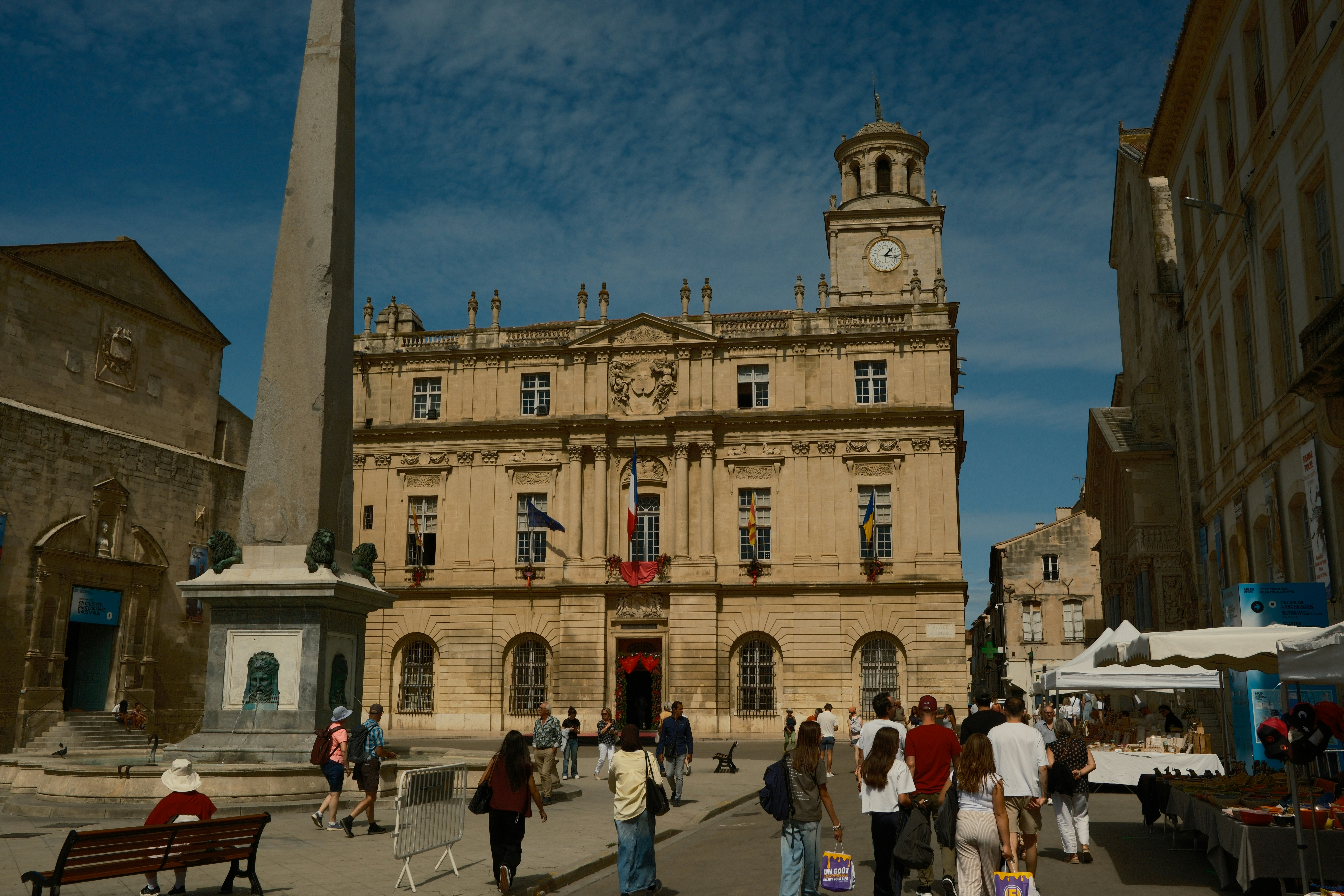 People walking in a town square with historic building.