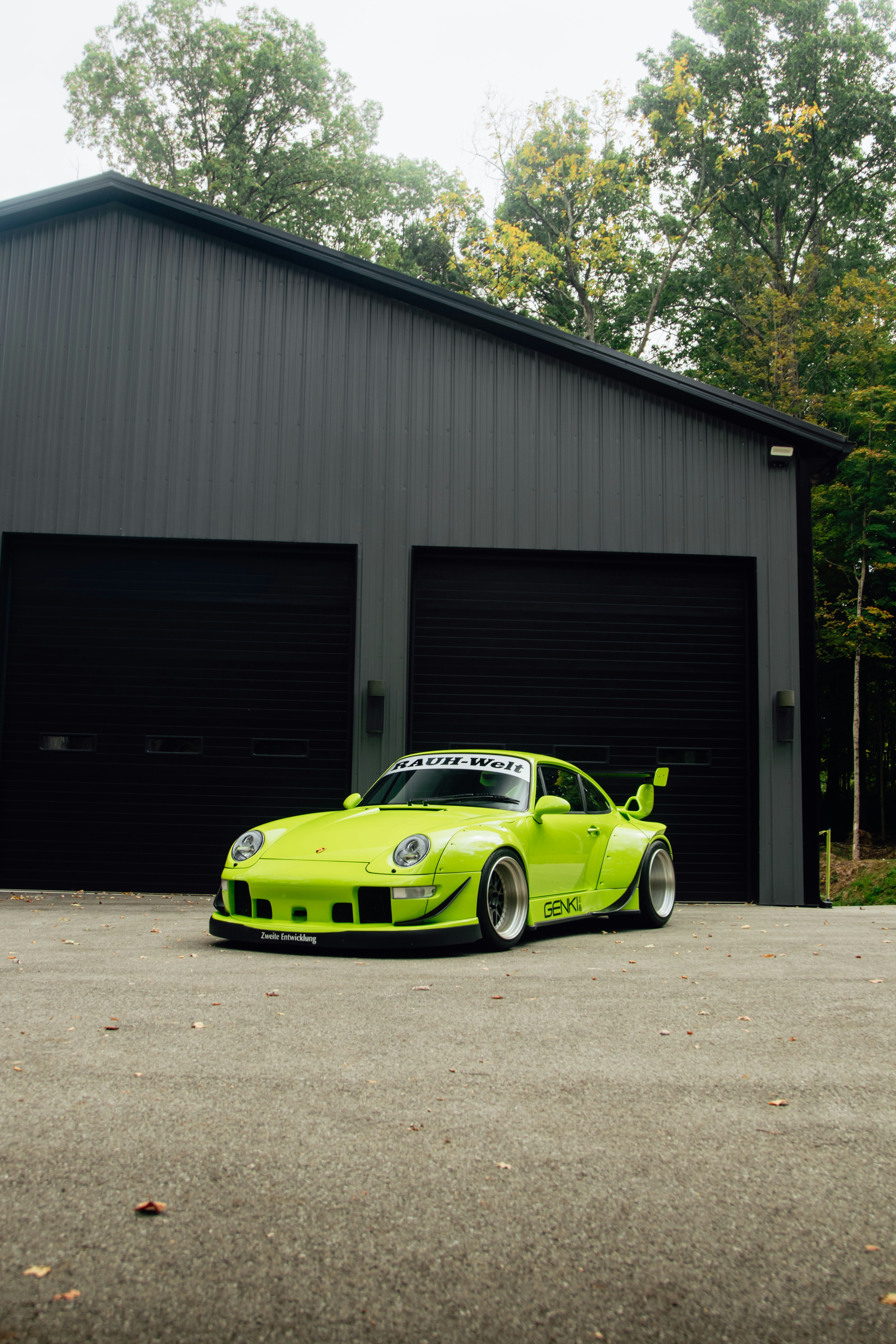 Lime green porsche 911 parked outside a dark garage.