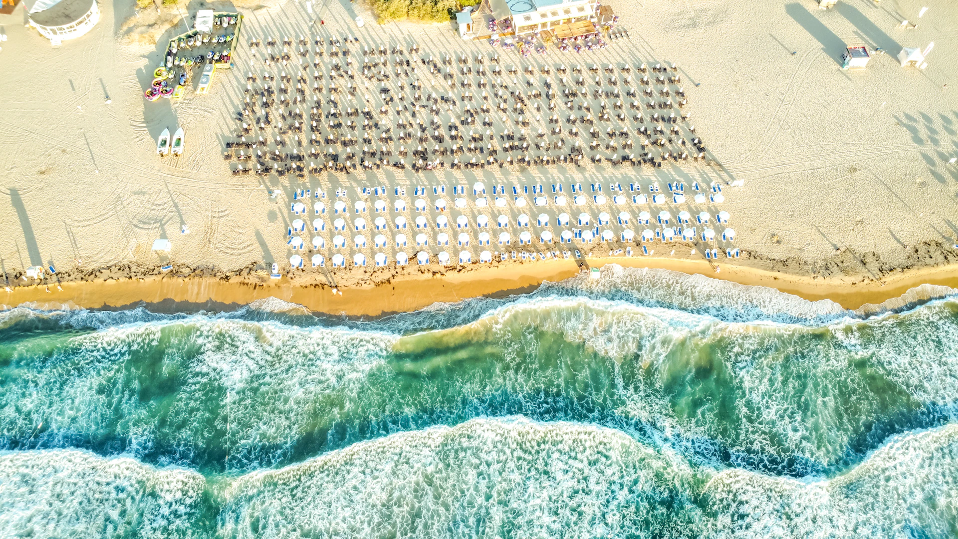 Rows of beach umbrellas on a sandy shore with waves