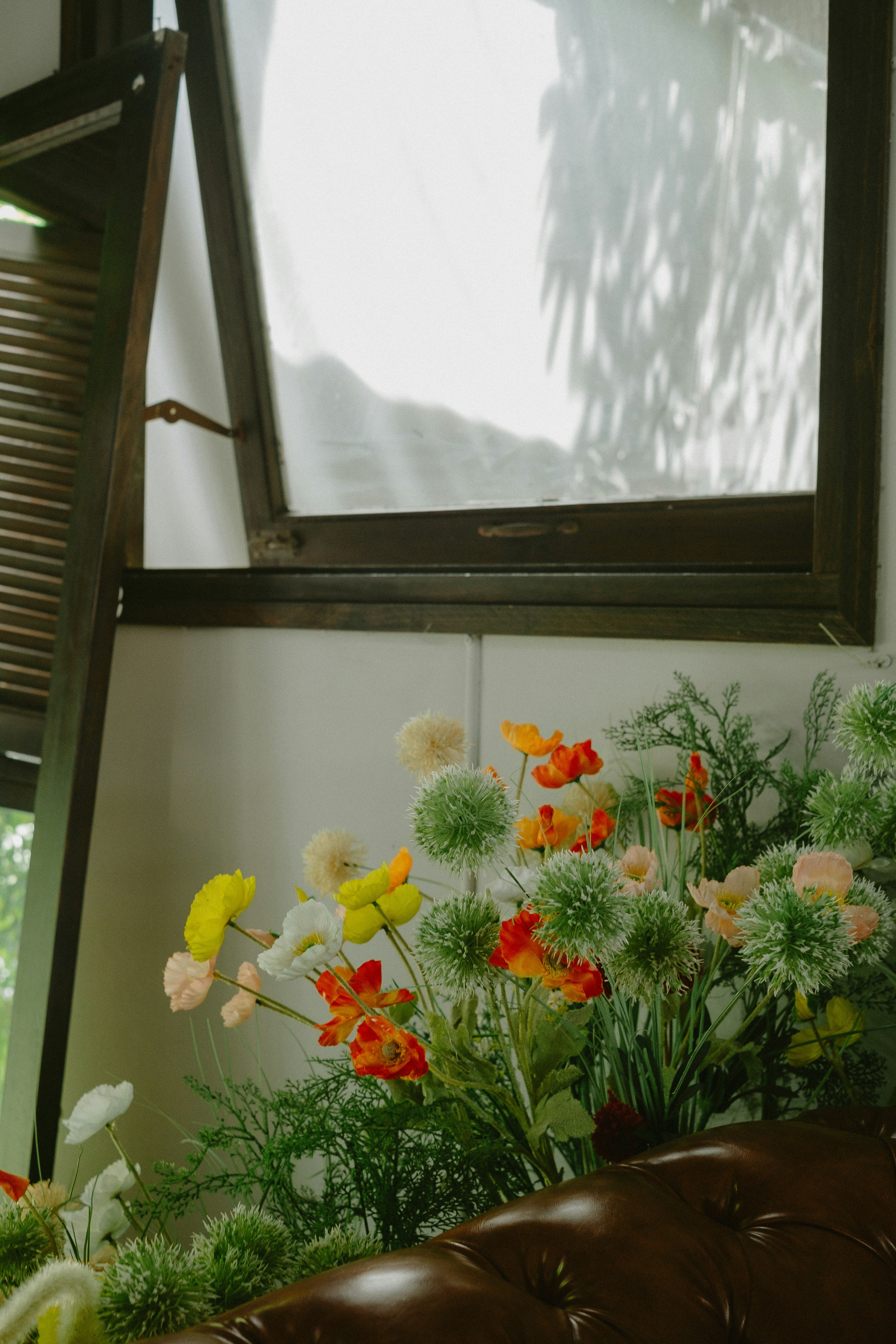 Colorful flowers on a windowsill with sunlight patterns.