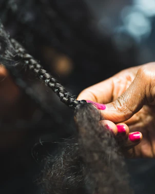 Close-up of hands braiding dark hair.