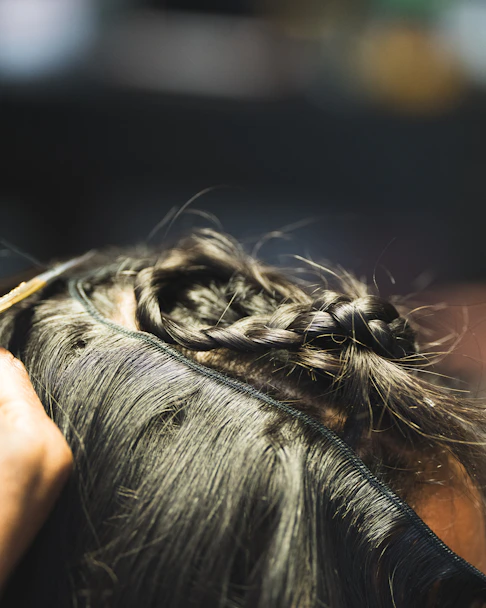 A person braiding dark hair with sunlight.