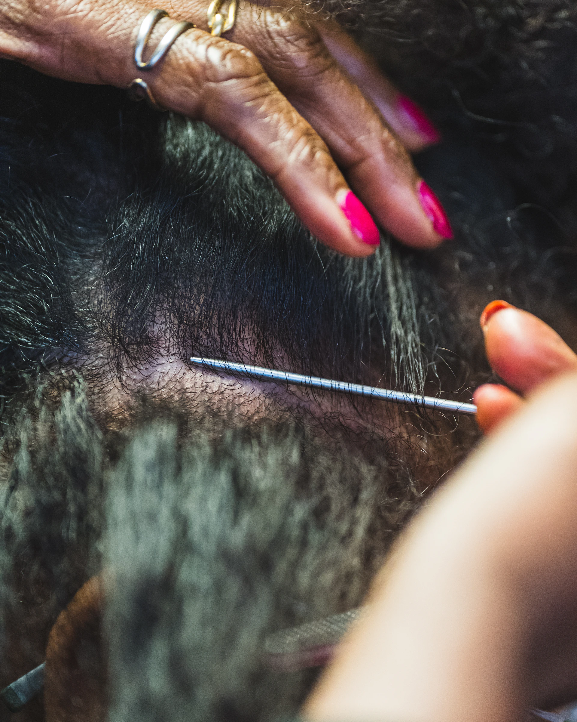 Close-up of hands styling hair with a needle.