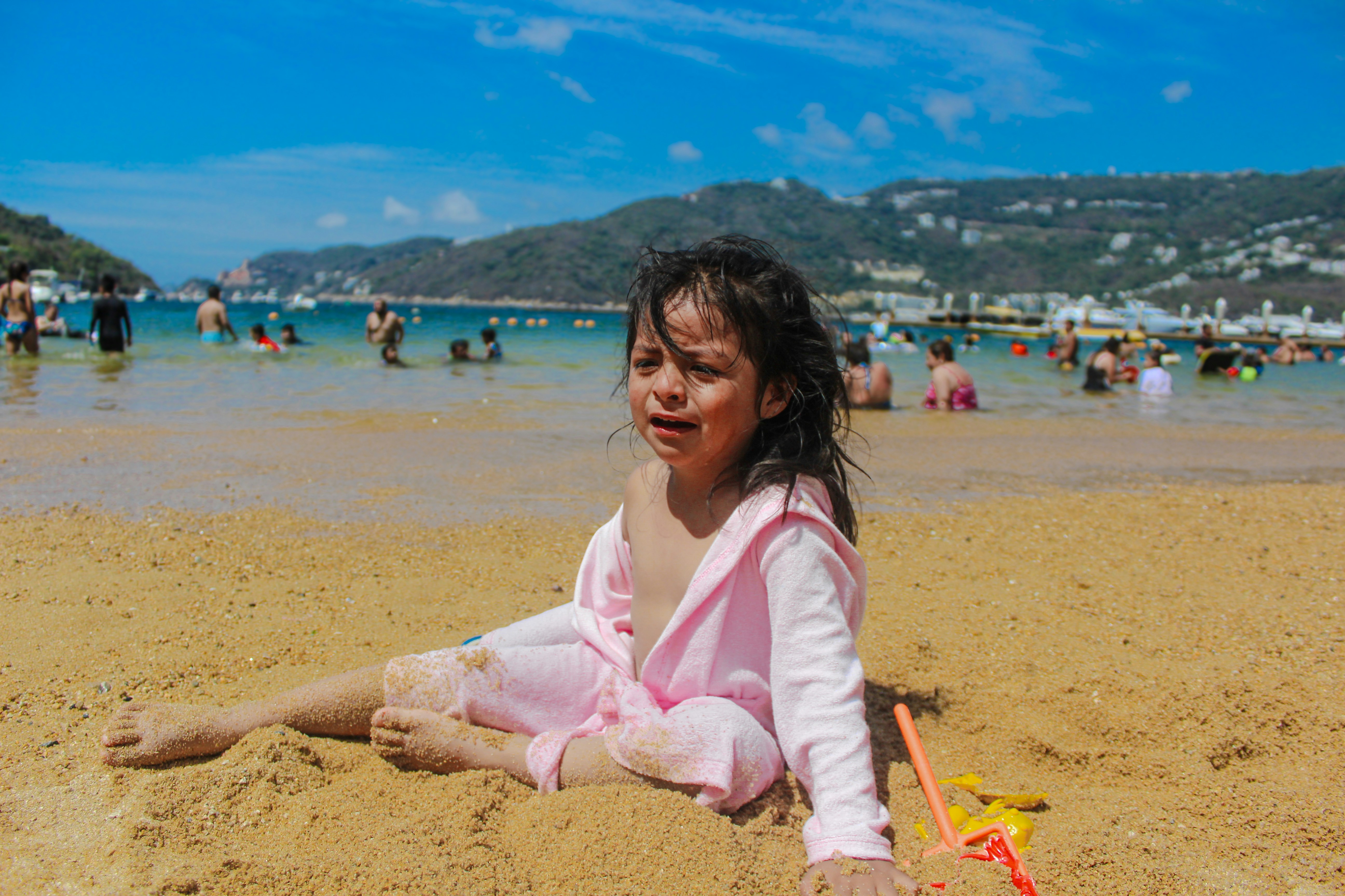 Crying girl sits on a sandy beach