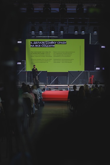 Speaker presenting on stage with audience watching