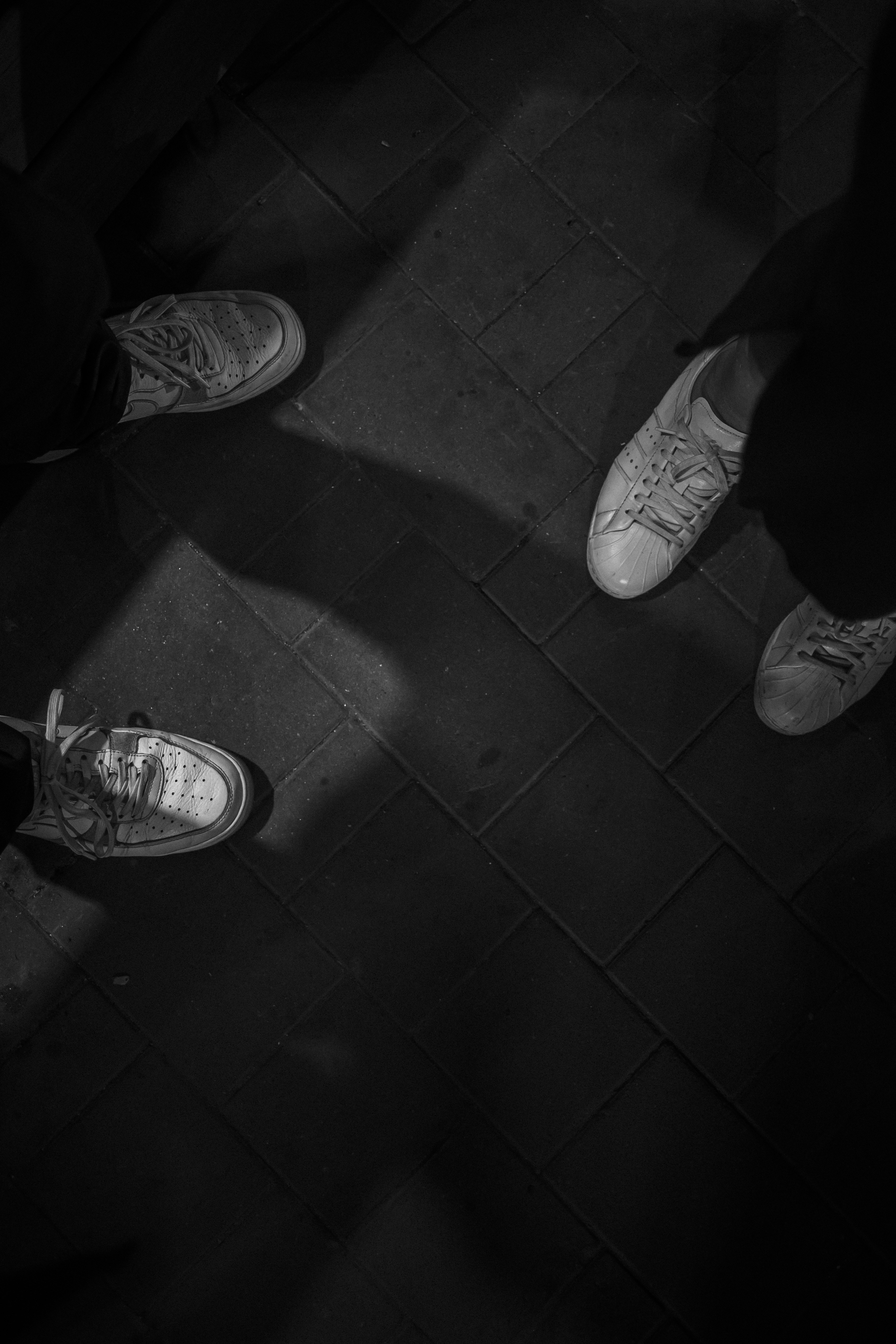 Four pairs of shoes on a brick walkway.