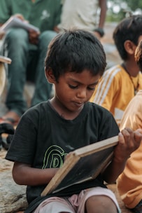 Young boy learning to write on a small blackboard.