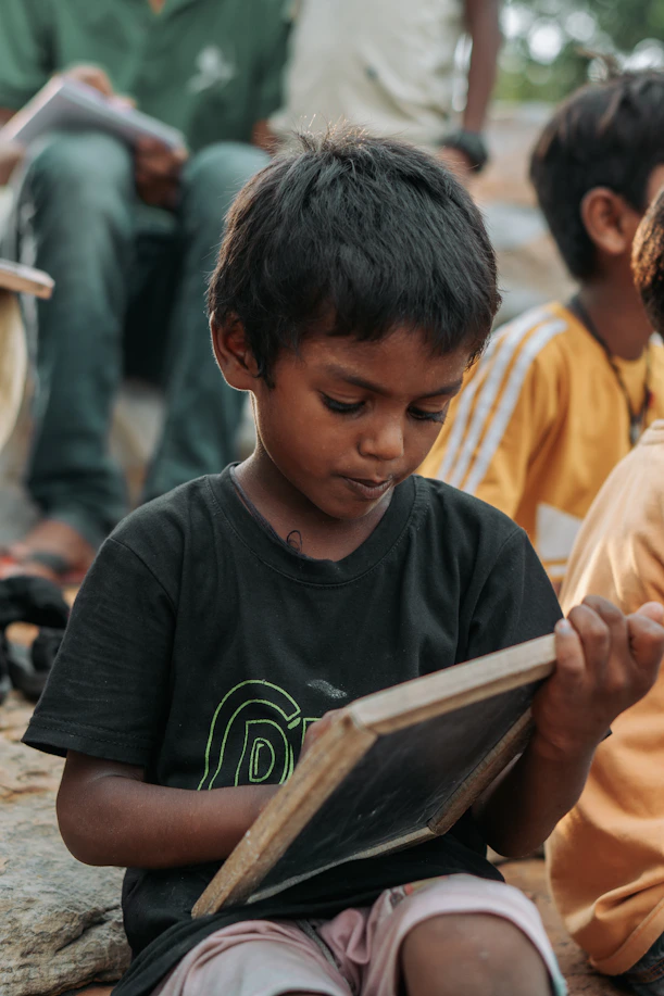 Young boy learning to write on a small blackboard.