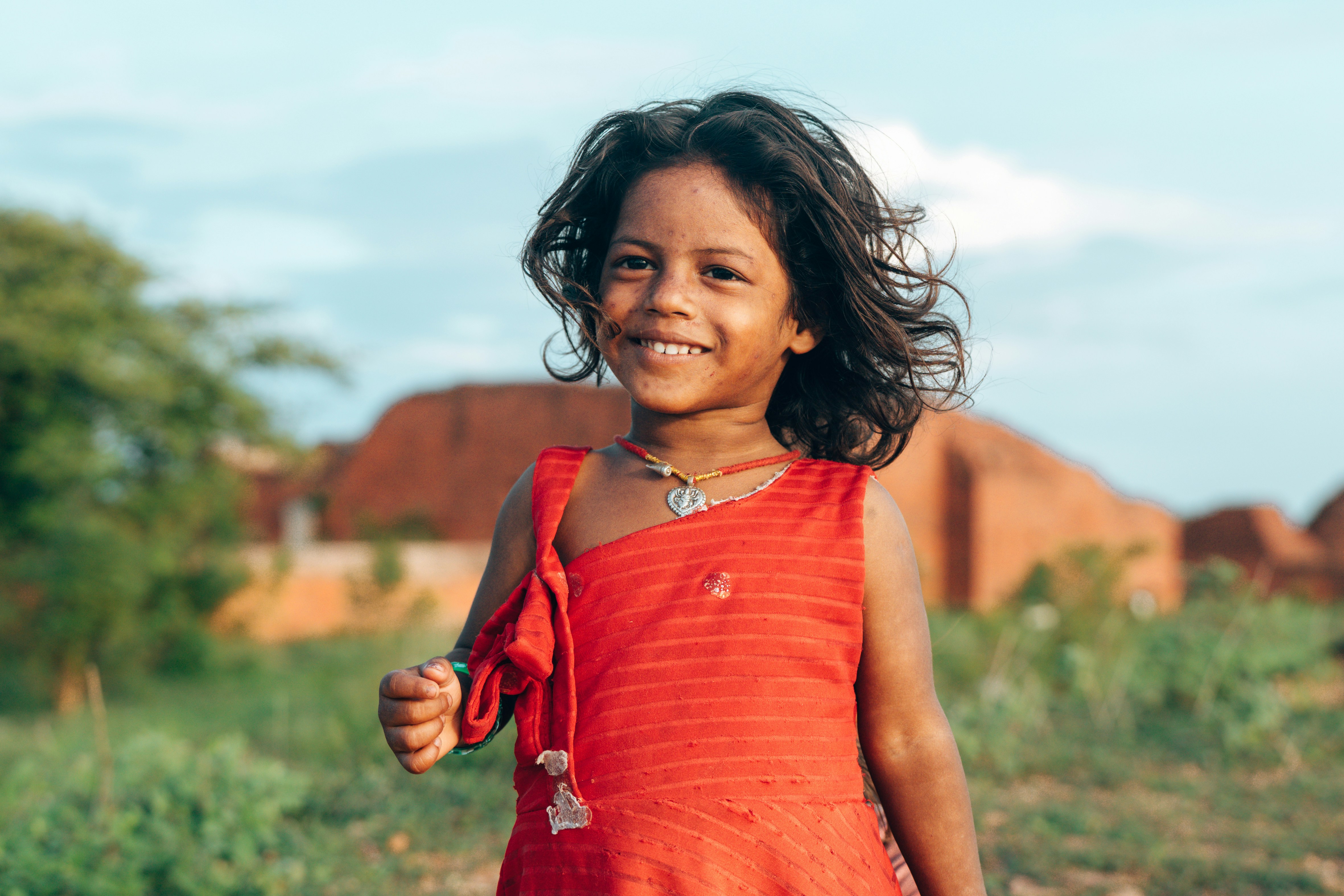 A smiling young girl in a red dress outdoors