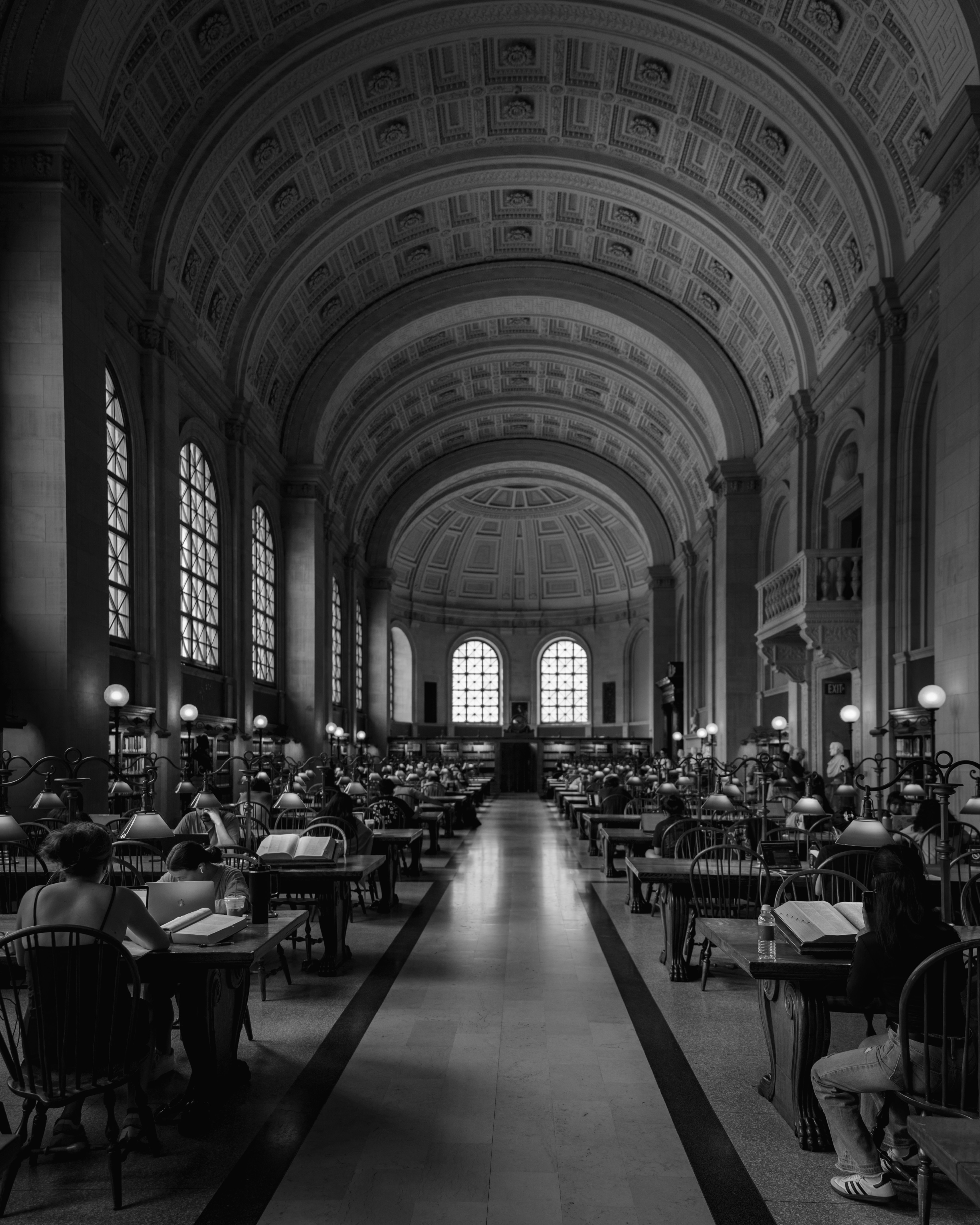 Pessoas lendo em um grande salão de biblioteca arqueado