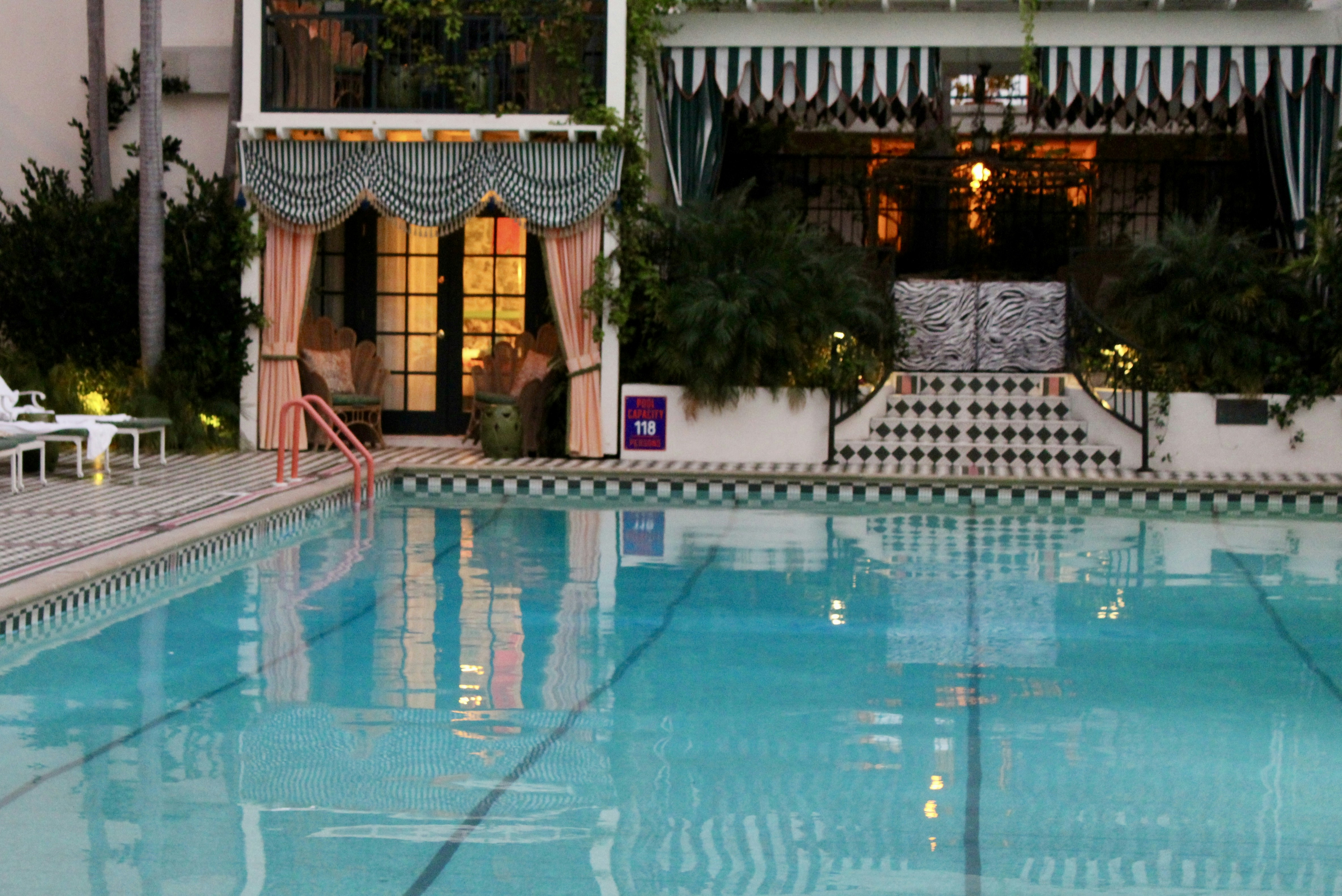 Swimming pool with striped awnings and greenery