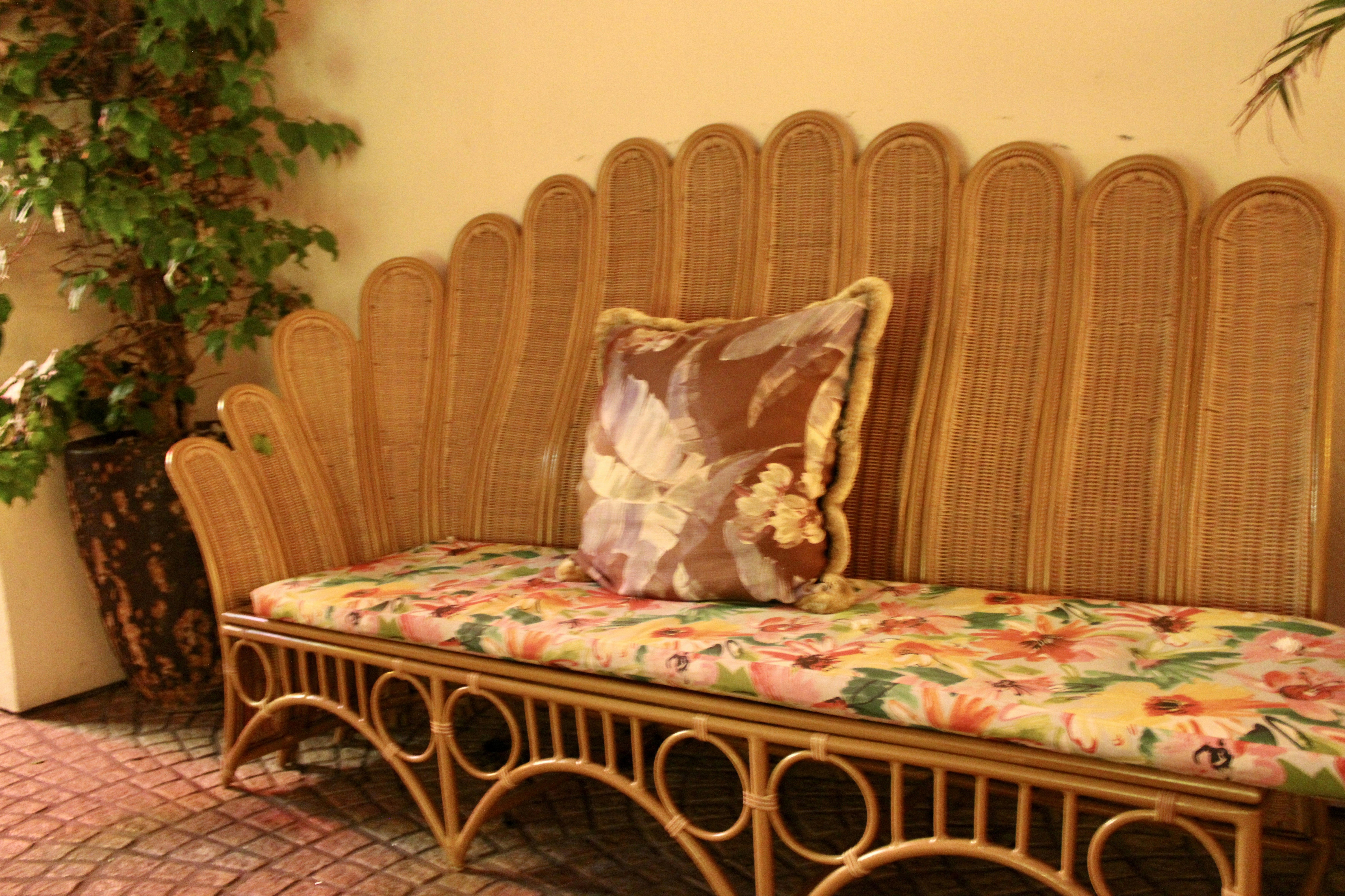 Wicker sofa with floral cushions and decorative pillow.