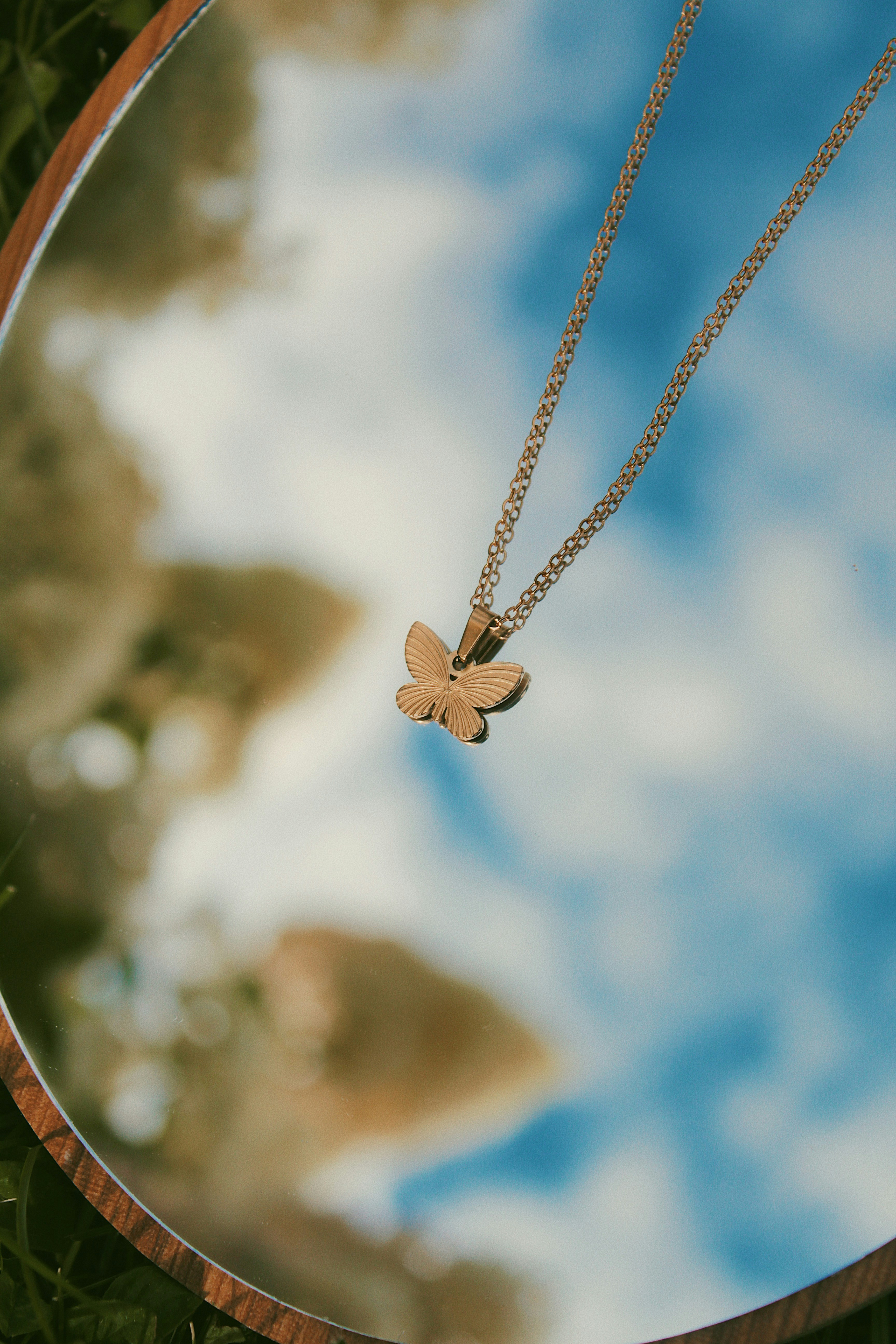 Gold butterfly necklace reflected in mirror