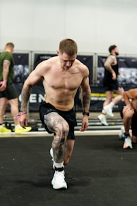Man with tattoos performing a lunge exercise