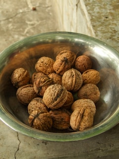 A metal bowl filled with whole walnuts