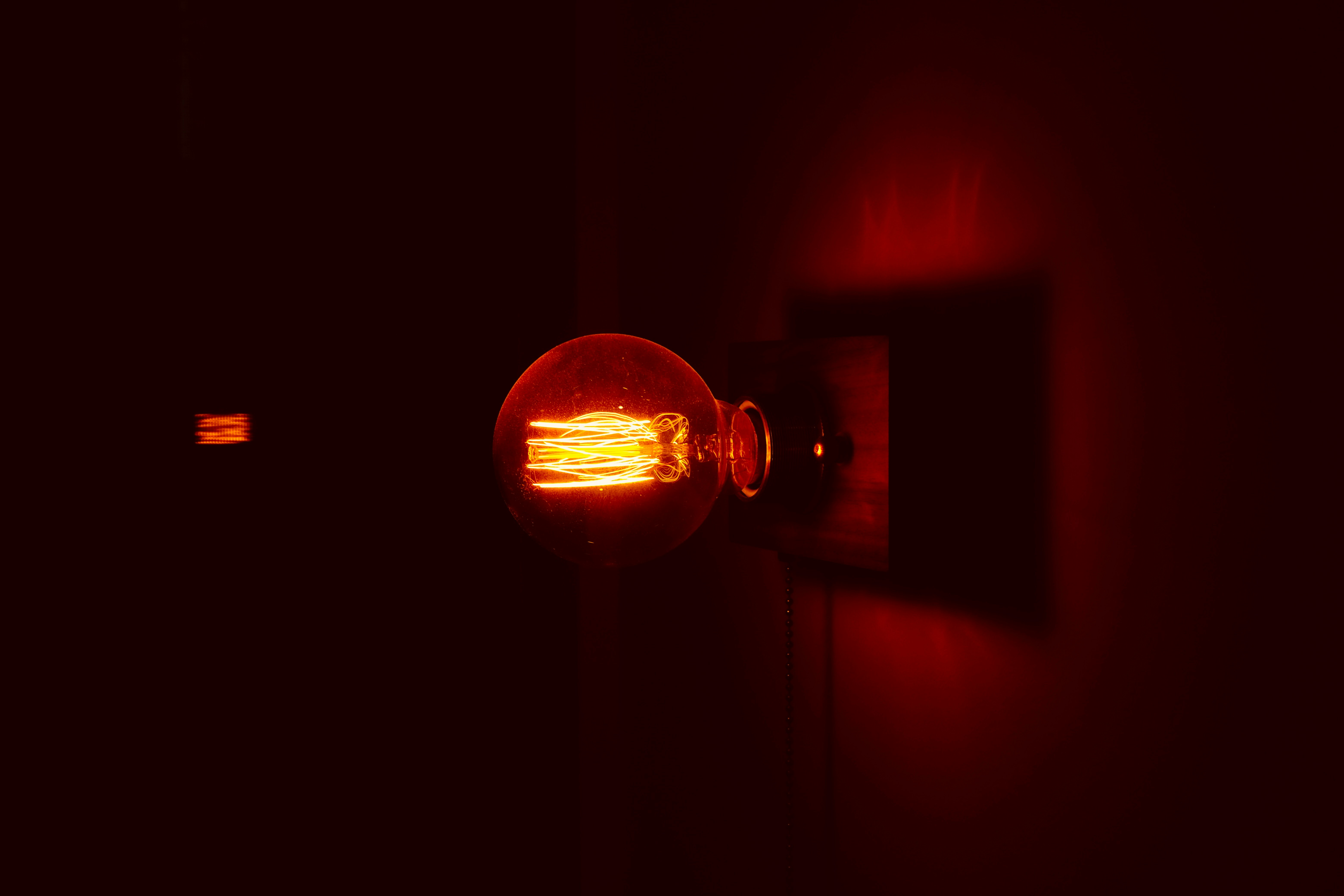 A single glowing edison light bulb in the dark.