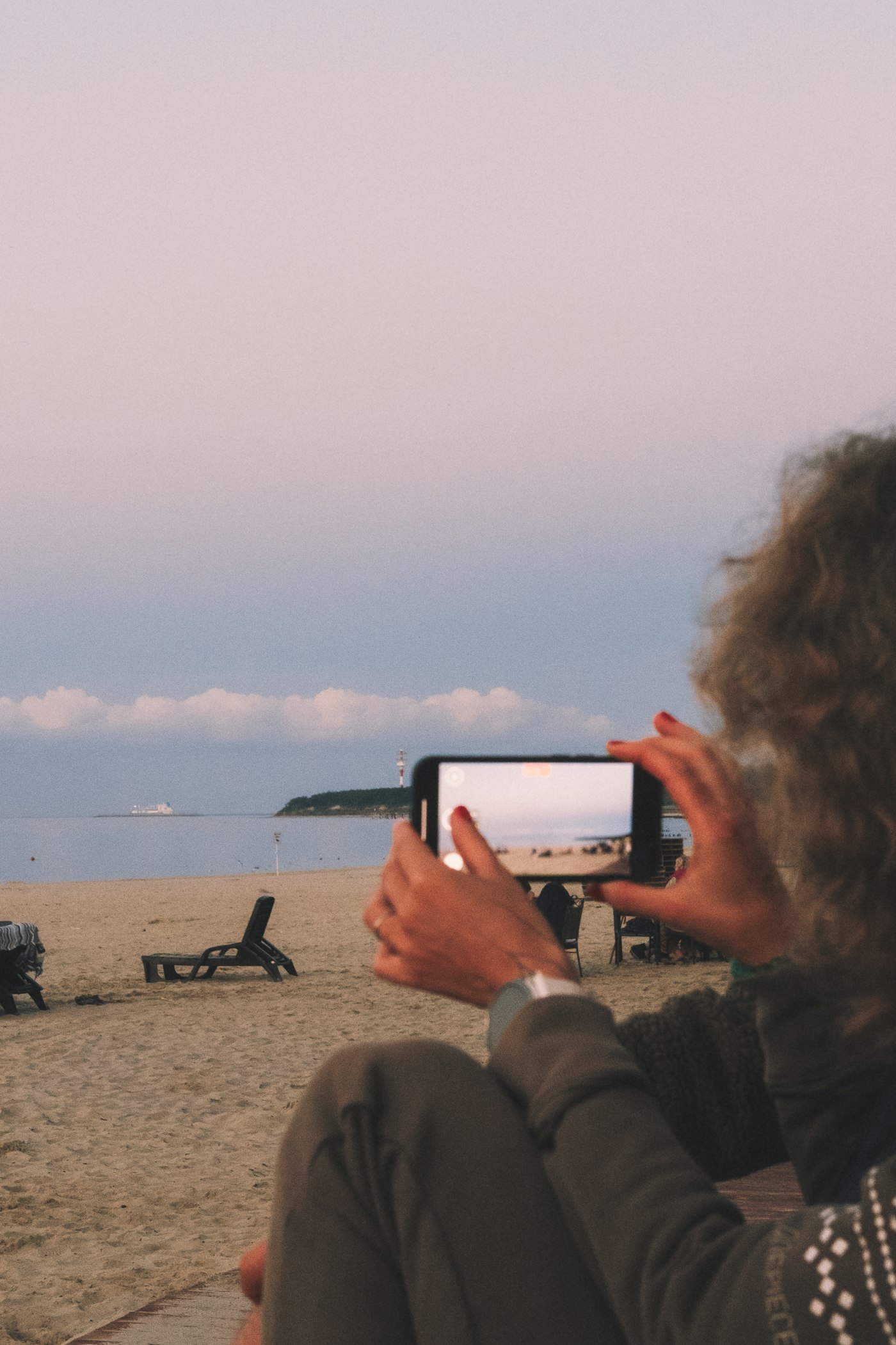 Créatrice de contenu filmant la plage avec téléphone — été 2026