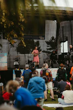 Musician performs on outdoor stage for seated audience.