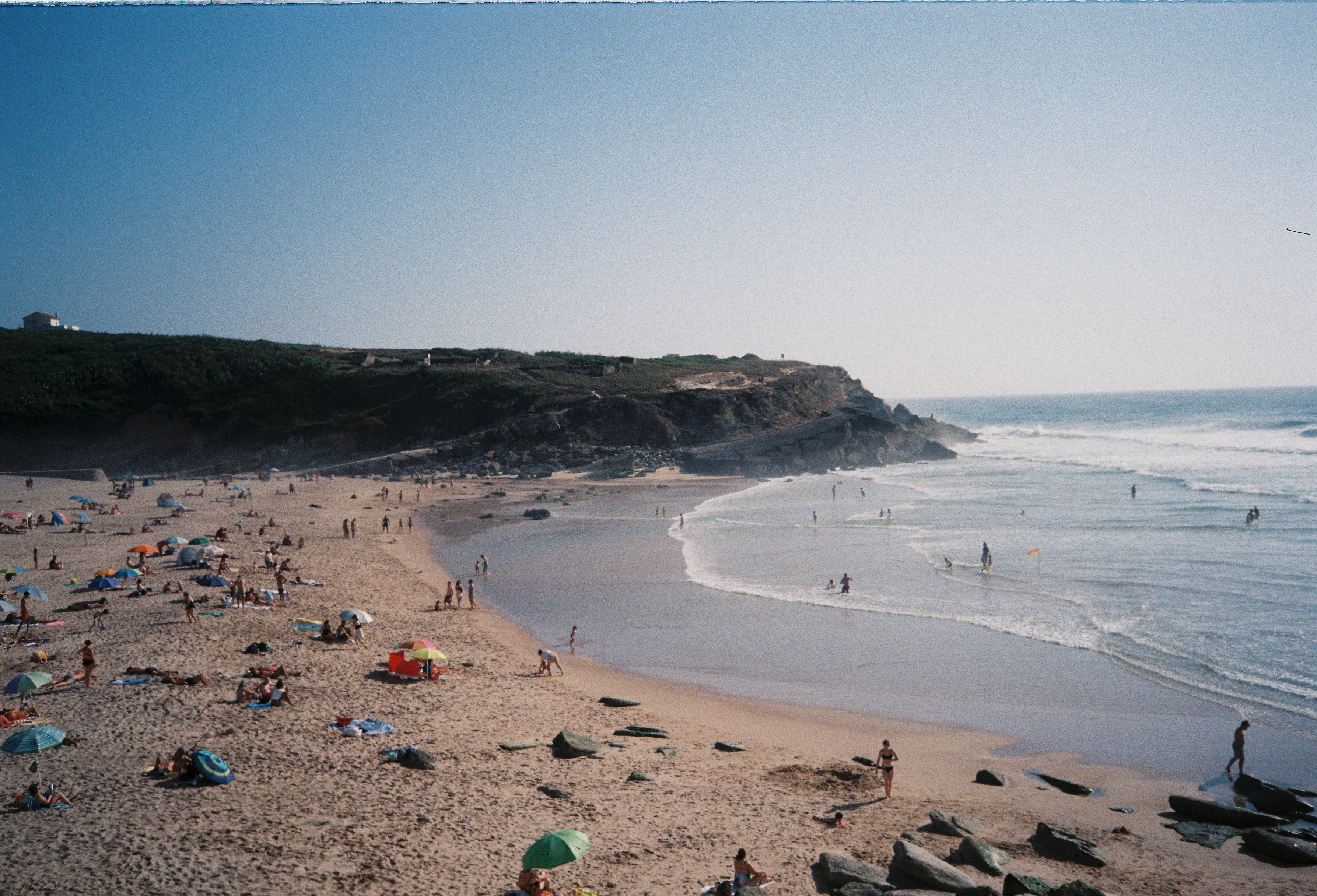 Überfüllter Strand mit Menschen, die sich sonnen und Wellen surfen