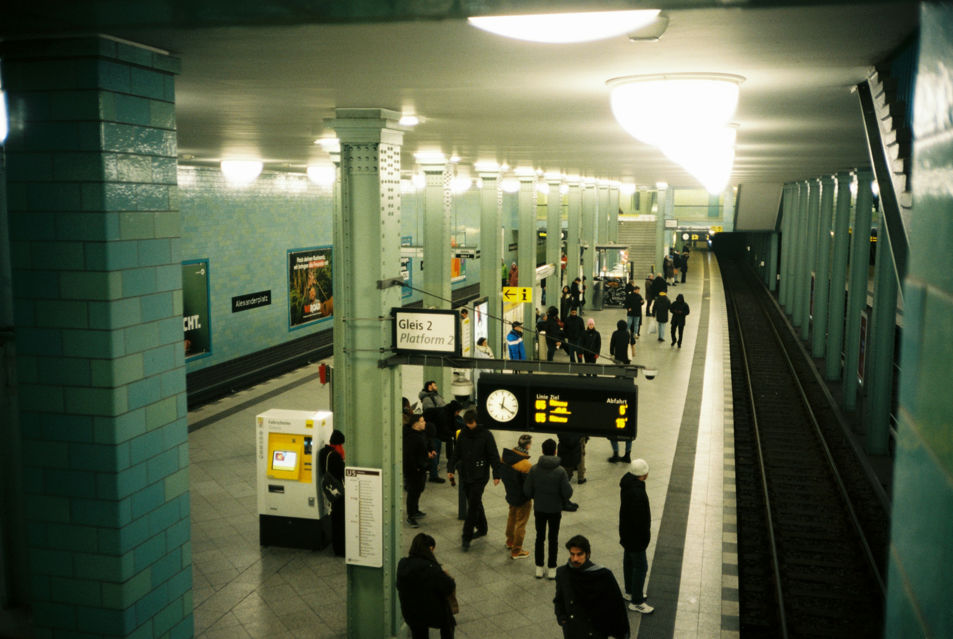 Menschen, die auf einem U-Bahnsteig warten, mit Zügen in der Nähe.