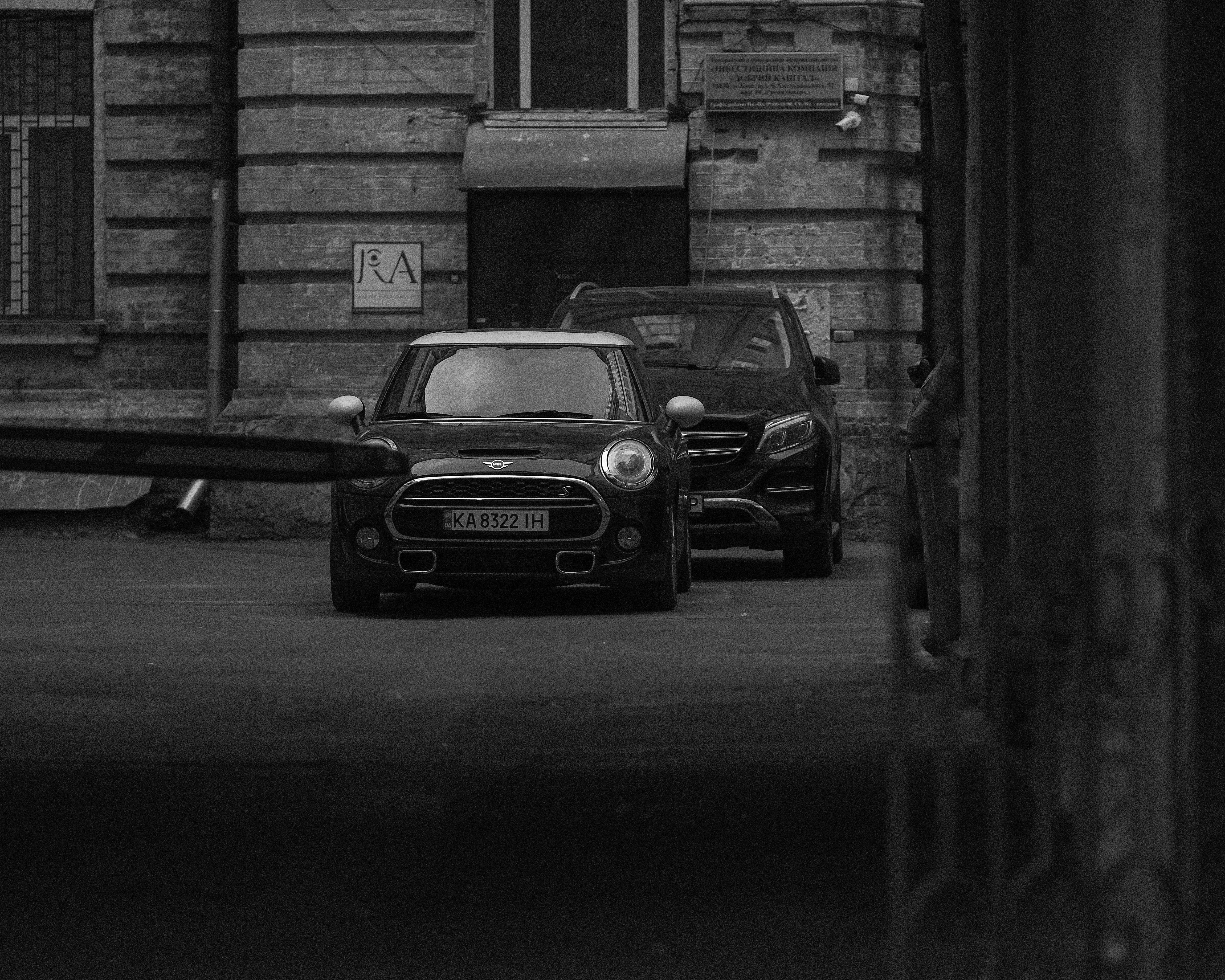 Two cars parked on a street in front of building.