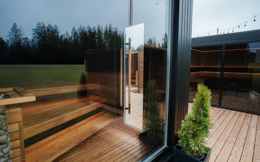 Sauna extérieur contemporain en bois et verre, à la tombée du jour.