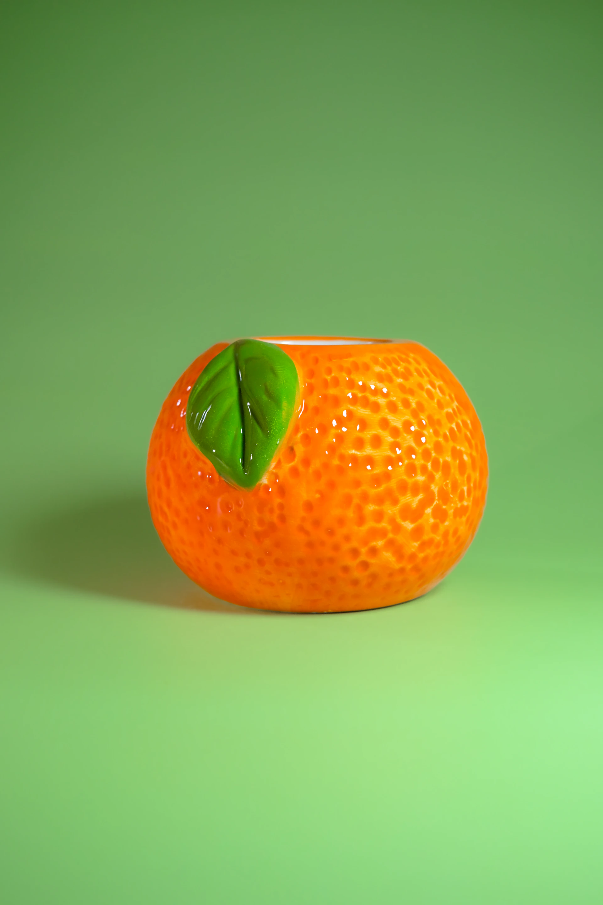 Orange-shaped ceramic pot with green leaf detail