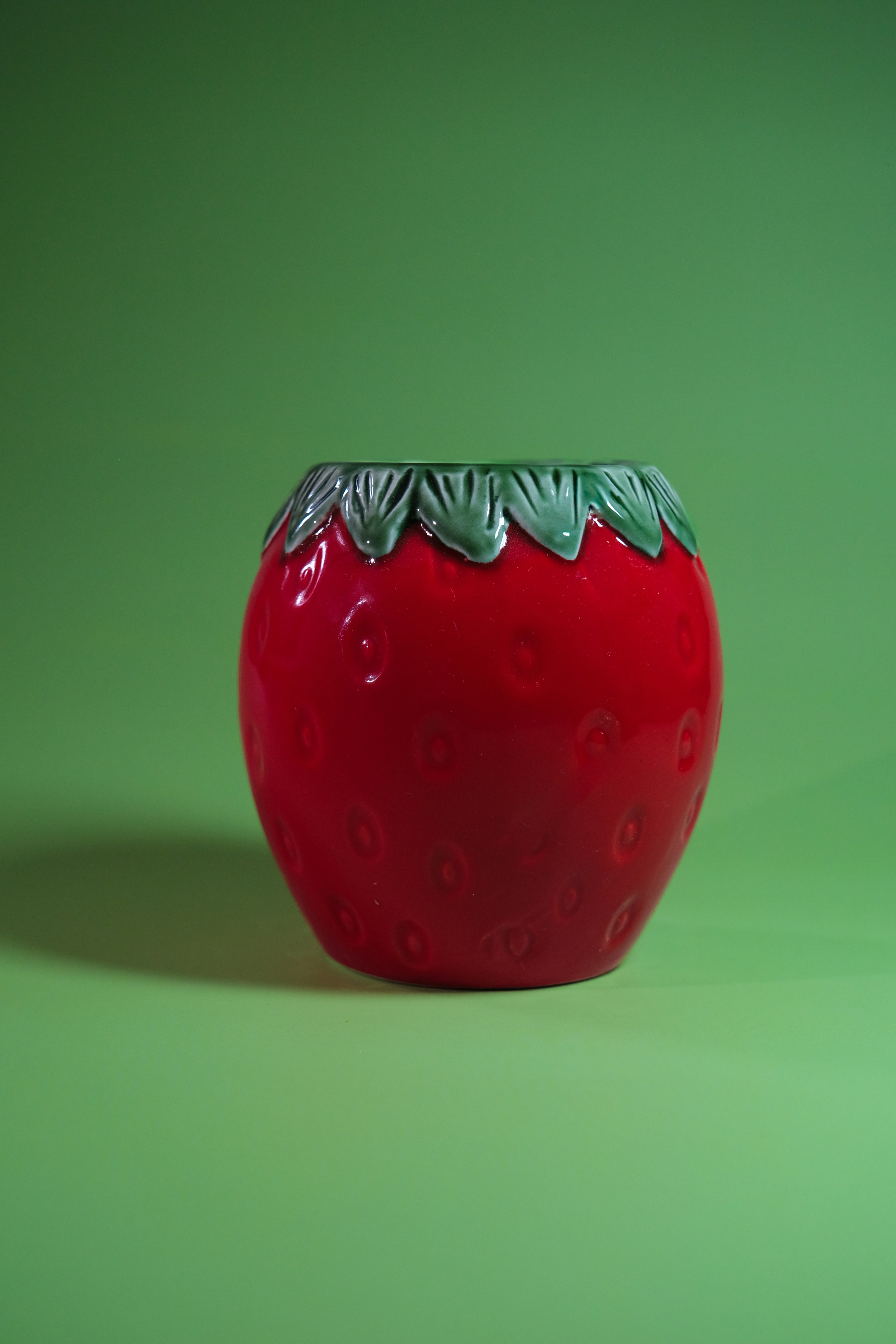 A red strawberry-shaped ceramic pot