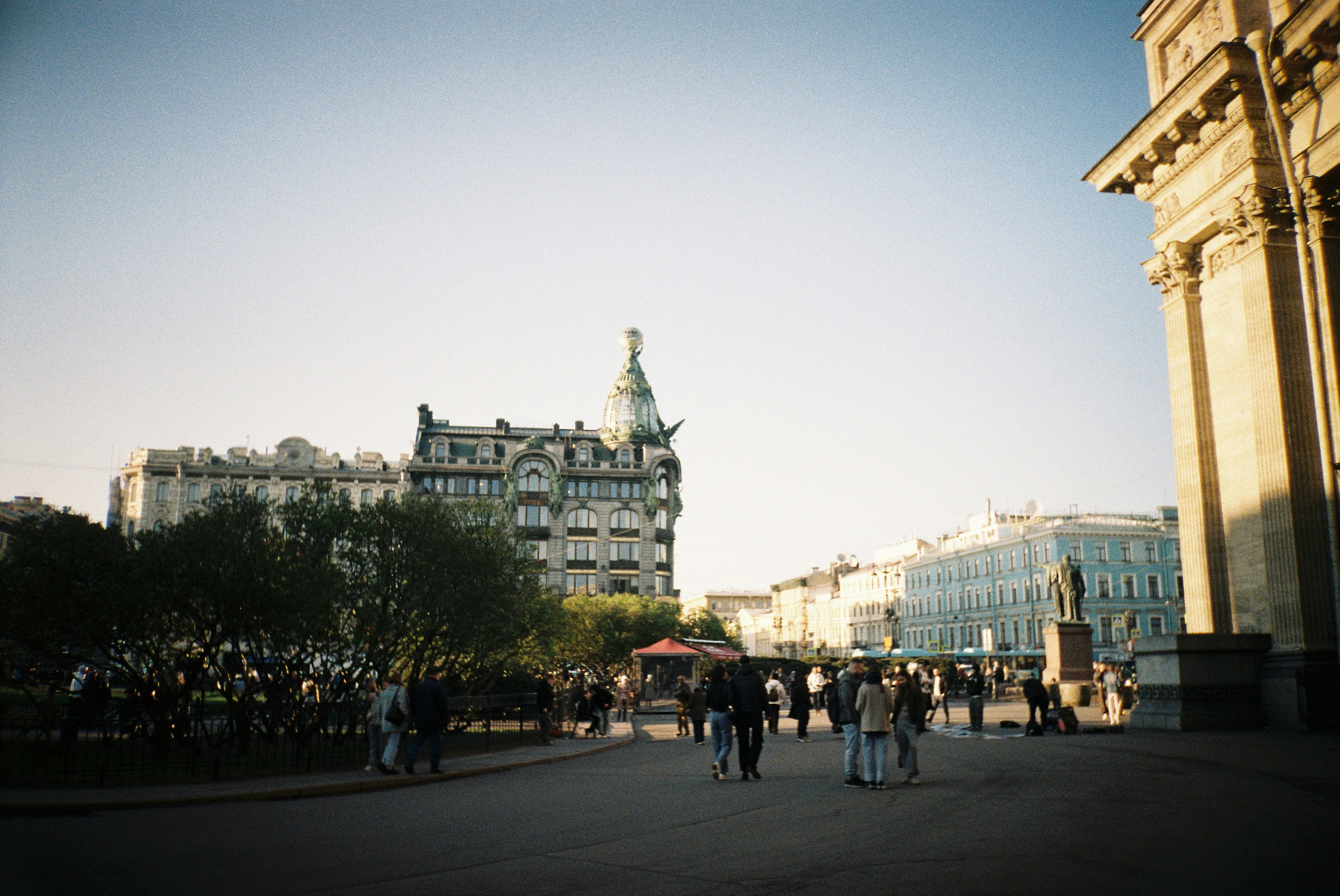 Des gens se promènent sur une place de la ville avec des bâtiments historiques.