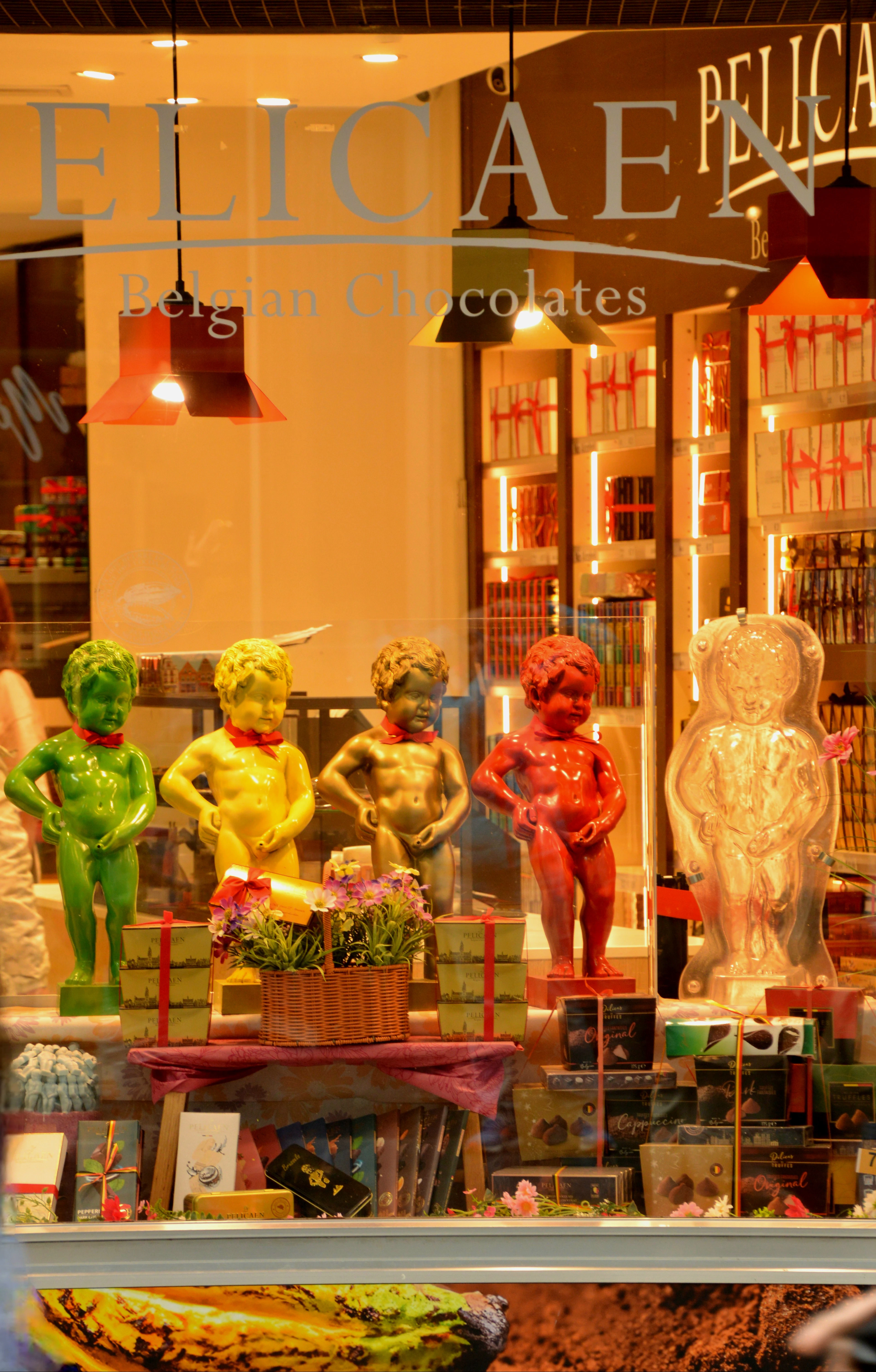 A Belgian chocolate shop window in Brussels filled with chocolate Manneken Pis figures in green, yellow, red and gold