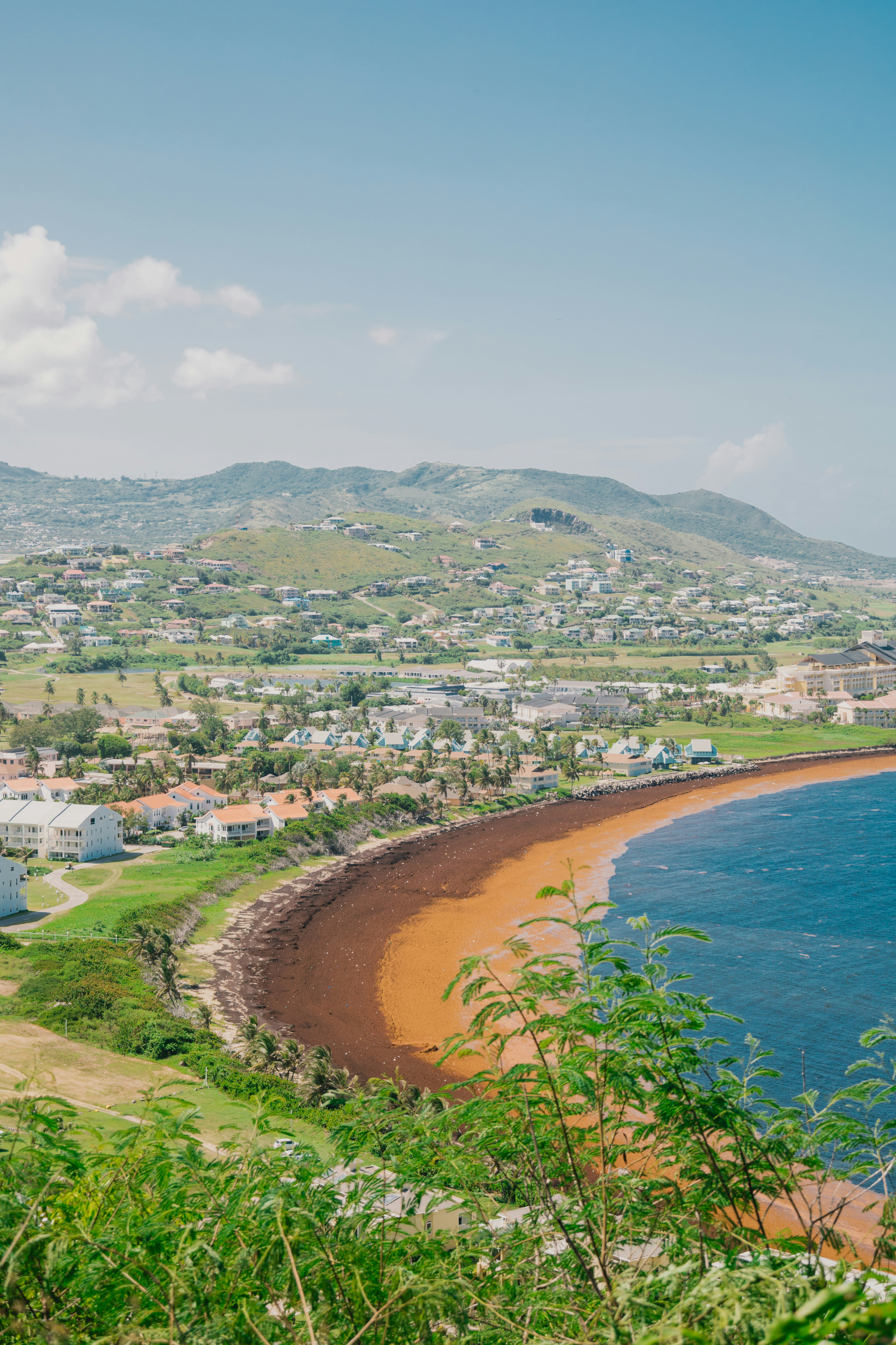 Küstenstadt mit braunem Sandstrand und blauem Meer.