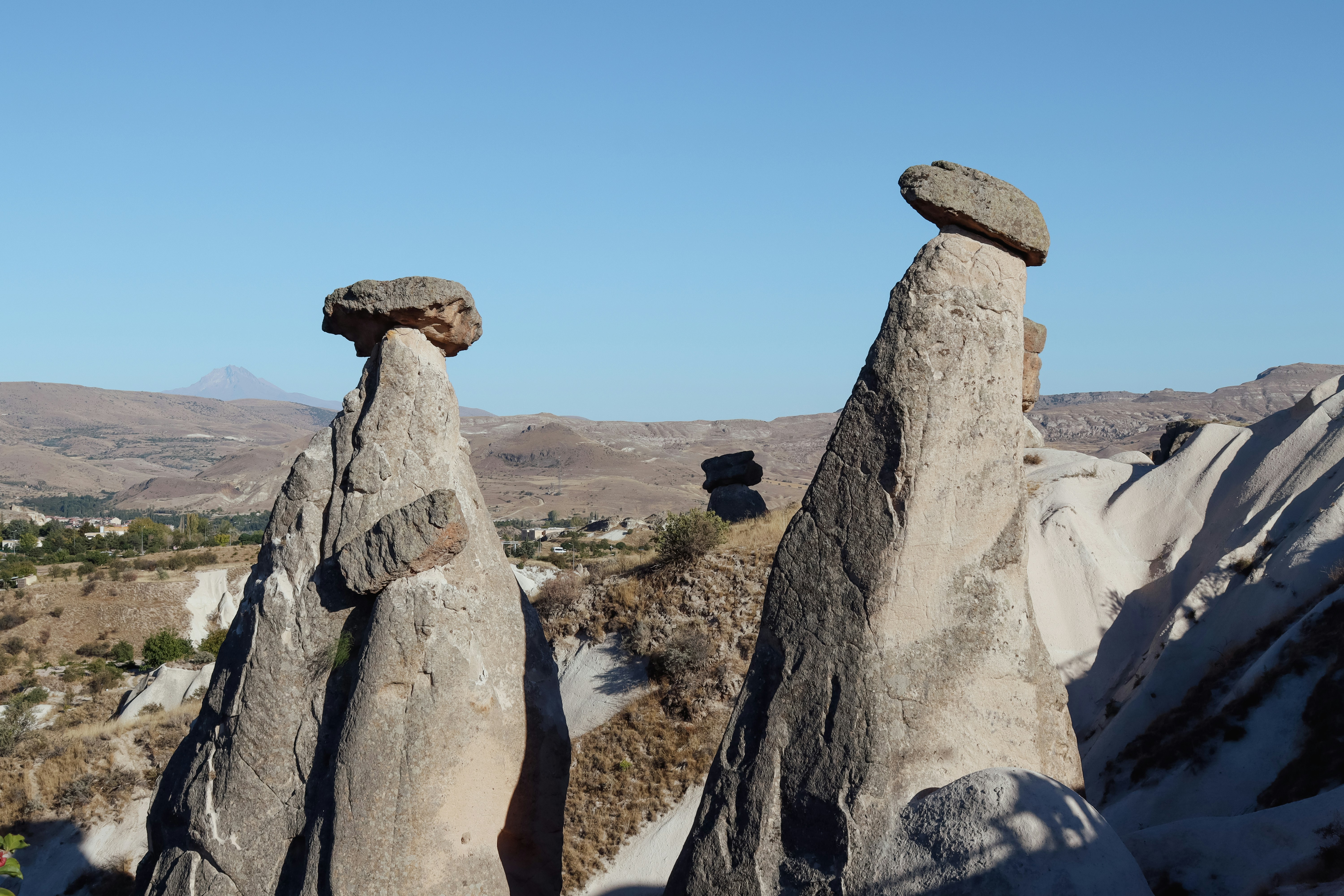 Two fairy chimneys with caps under clear sky