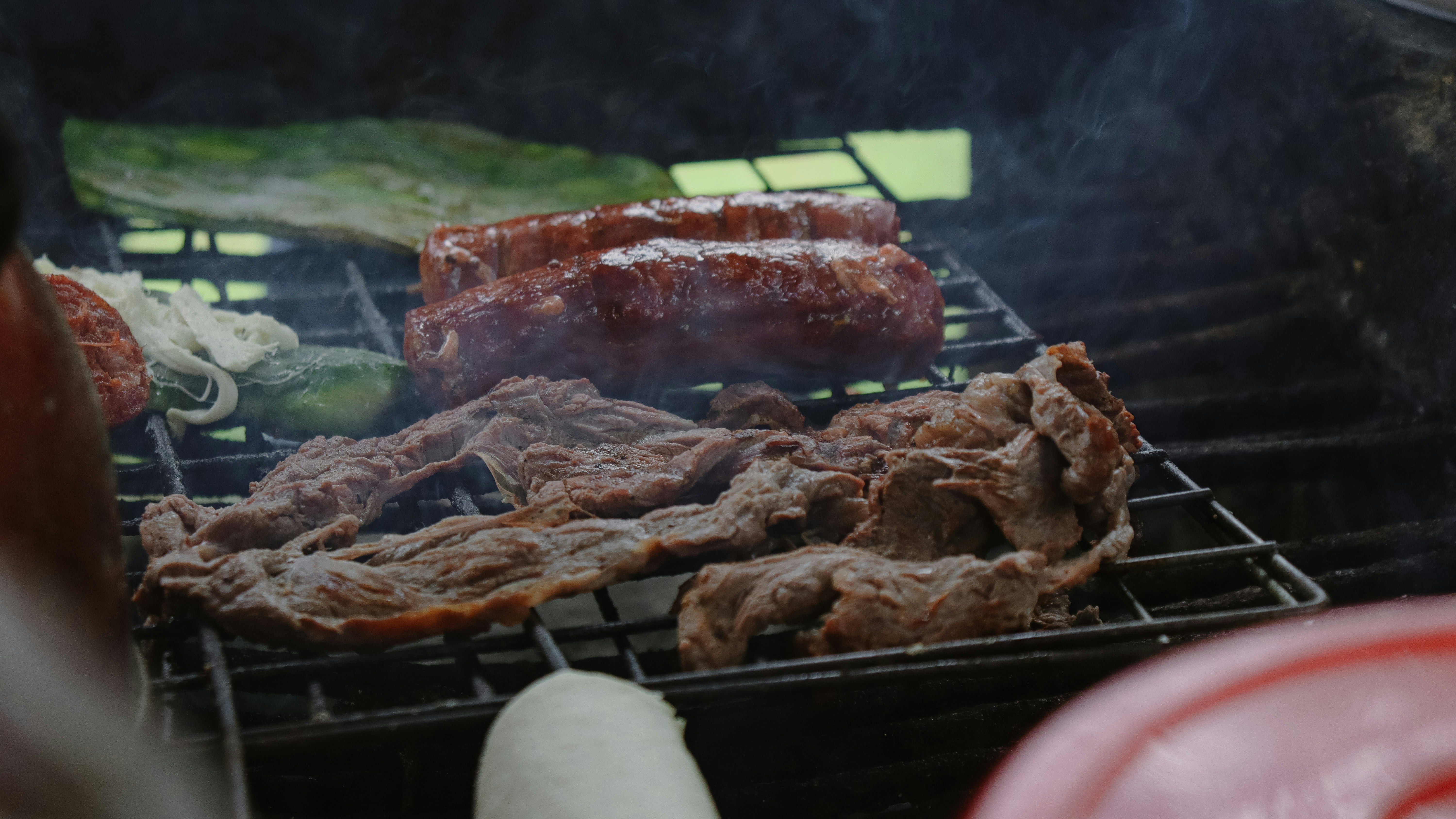 Sausages and meat cooking on a barbecue grill.