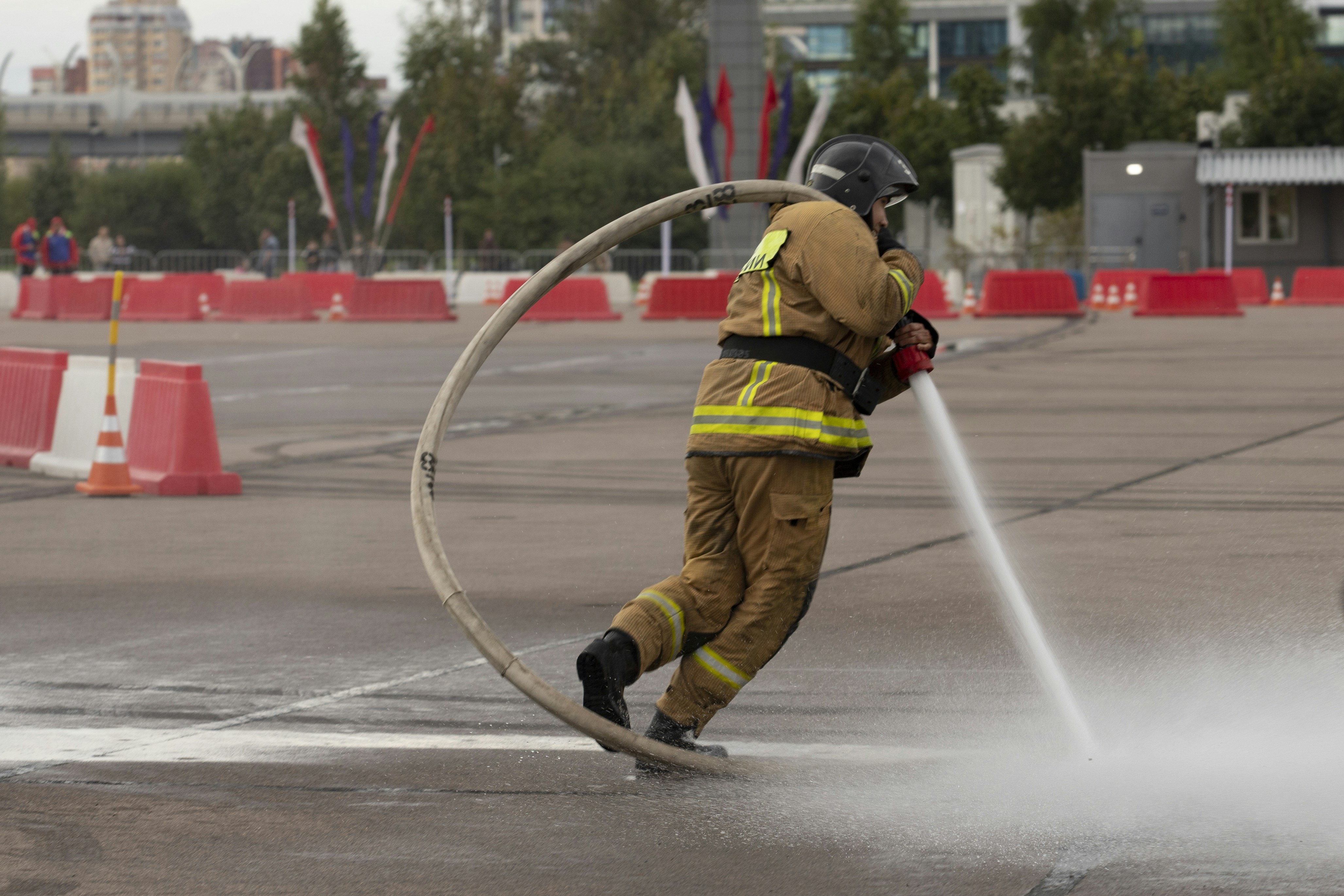 Firefighter sprays water through a large hose loop.