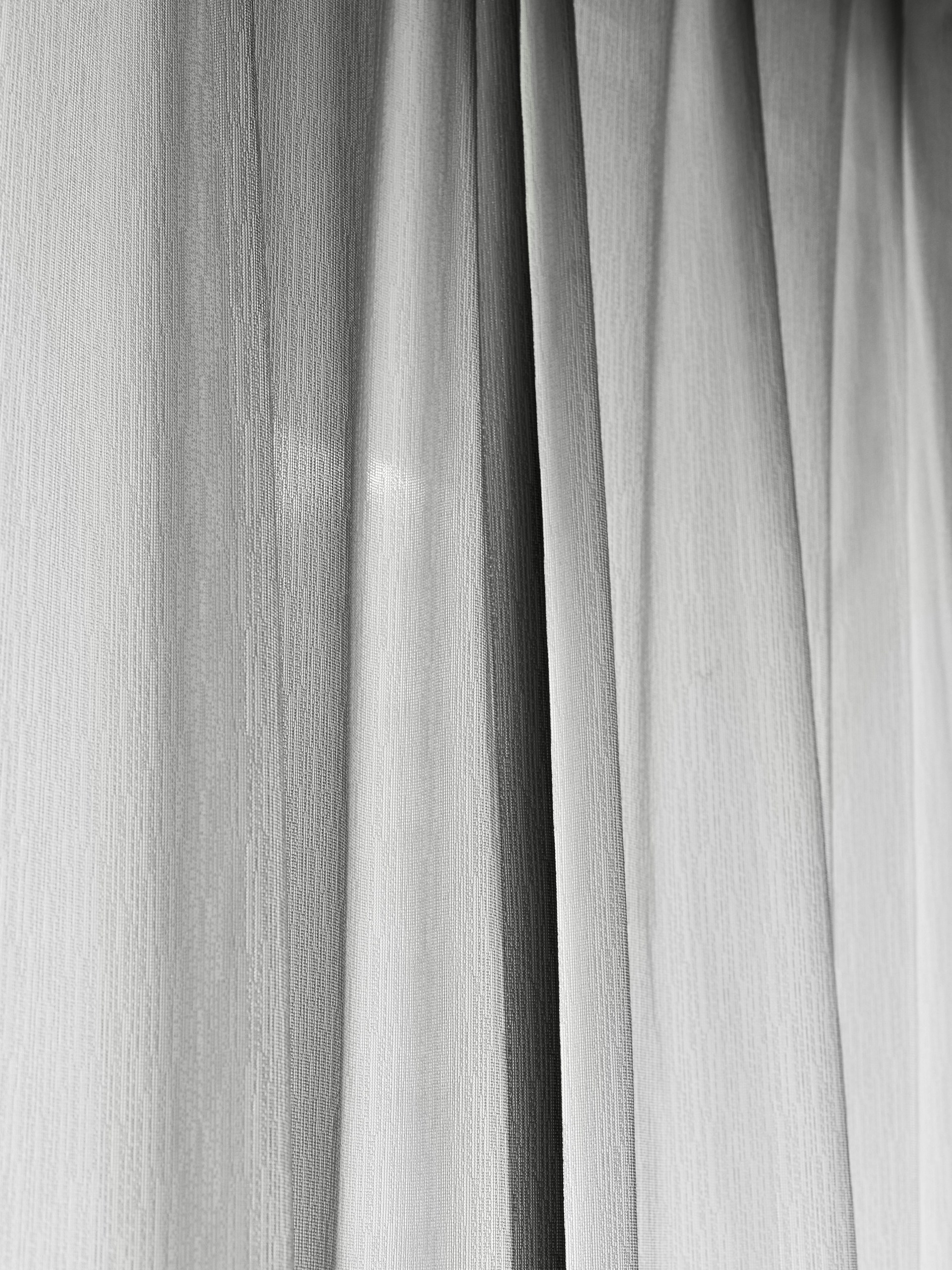 Soft folds of sheer white curtains with subtle light.