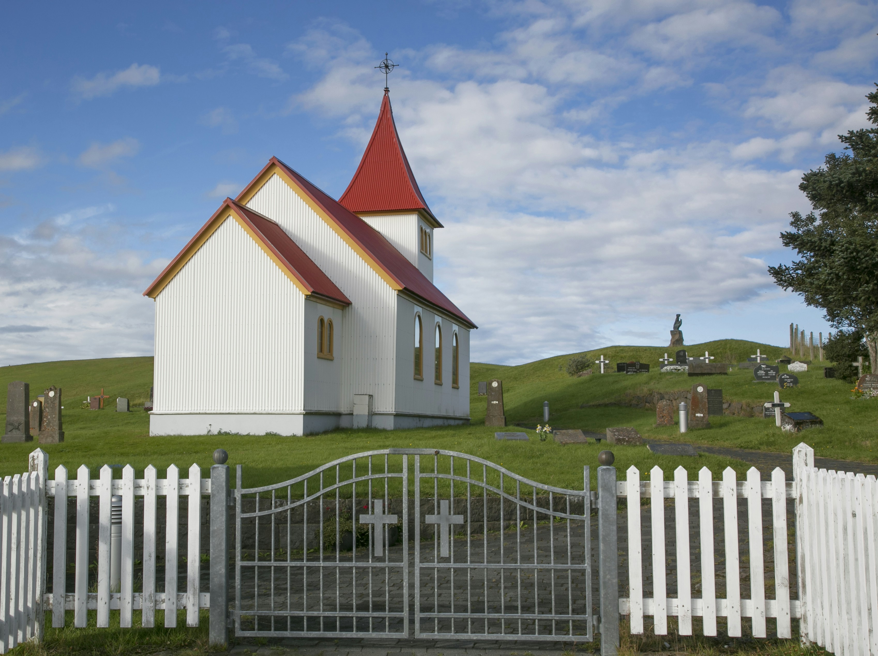 White church with red roof and graveyard