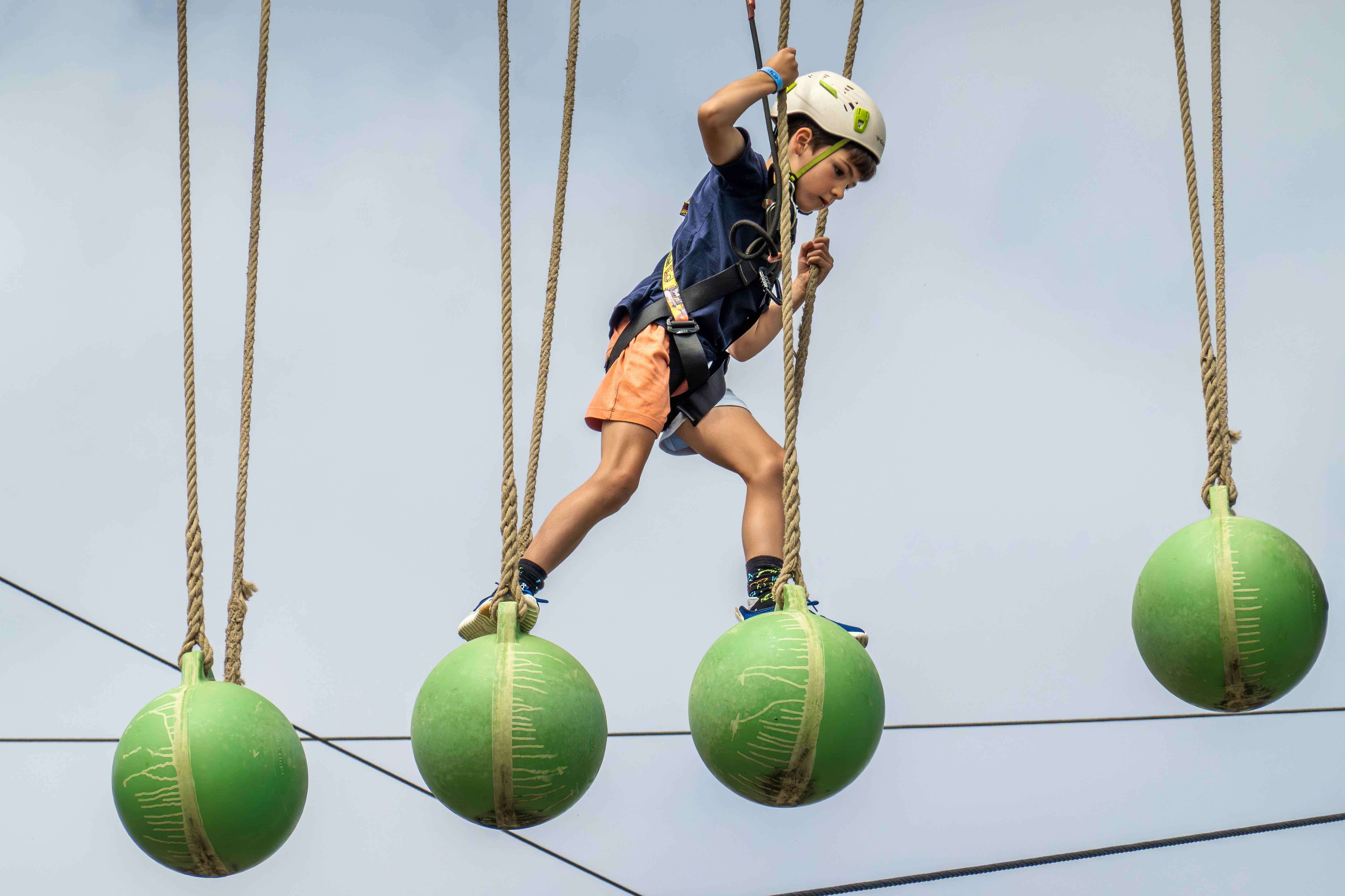 Boy on an adventure course balancing on green balls